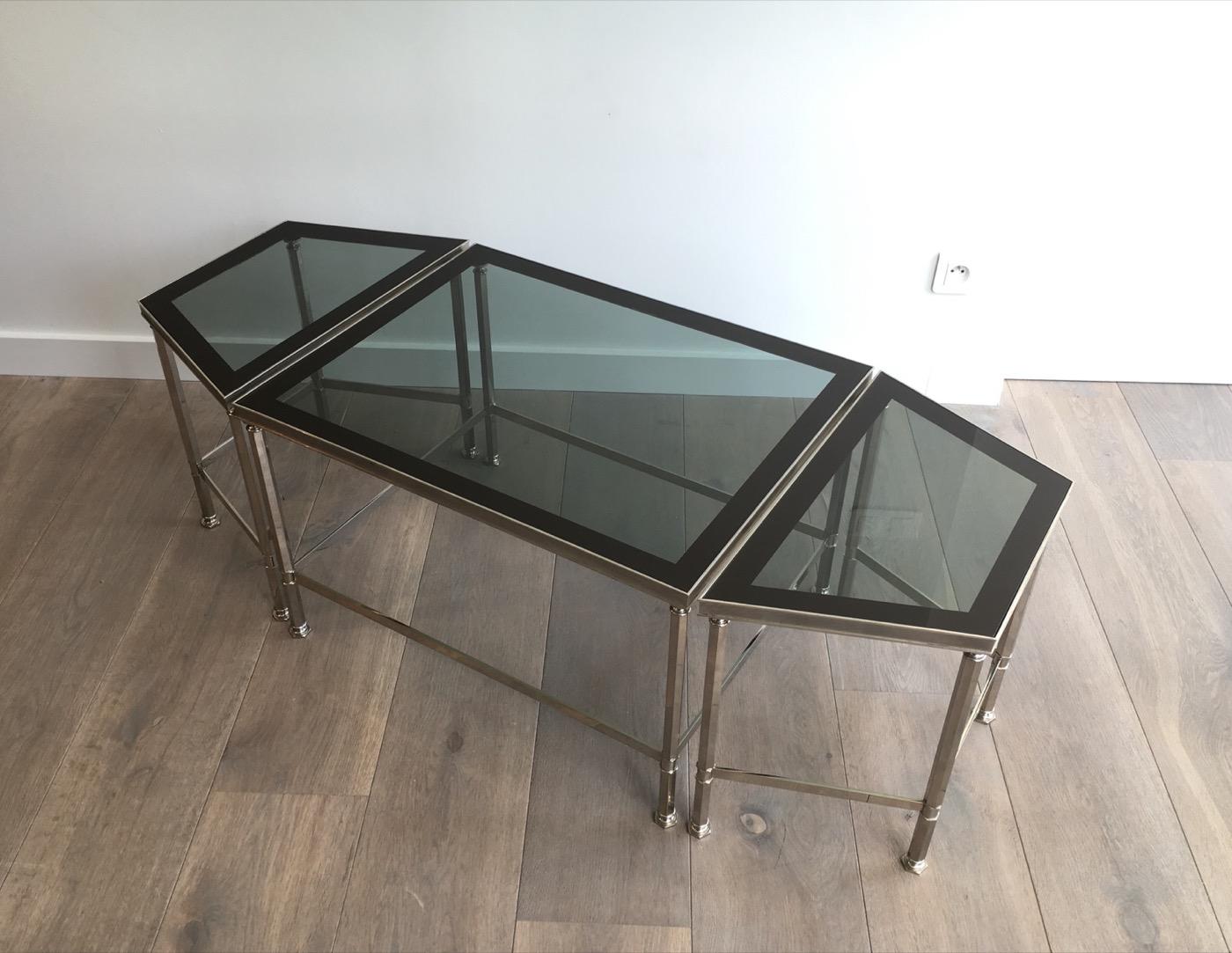 This rare tripartie coffee table is made of nickel with blueish glass shelves lacquered all around. This is a French work, circa 1940.