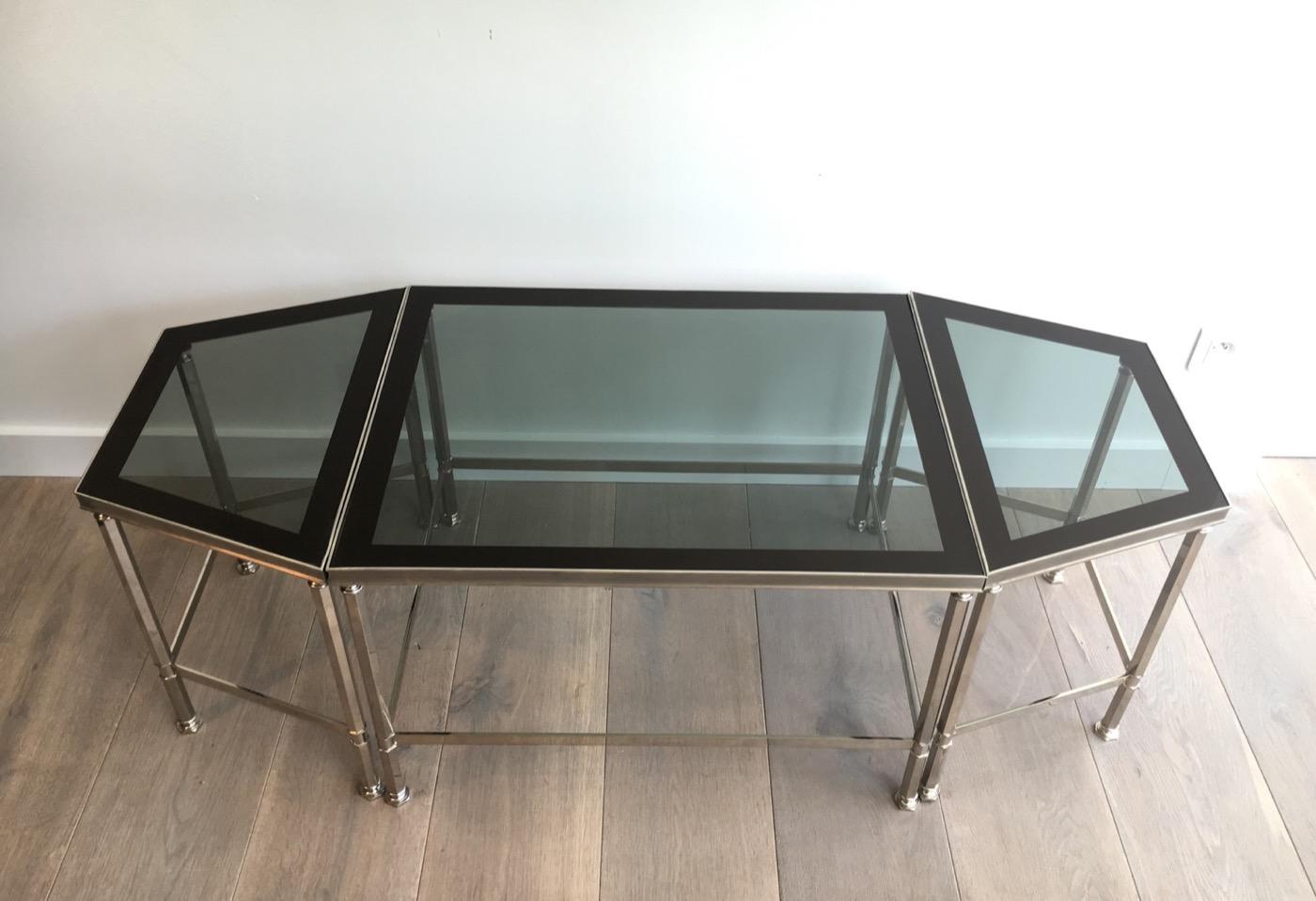 This rare and very elegant neoclassical style tripartite coffee table is made of nickeled brass with glass tops surrounded by a lacquered line. This is a French work. Circa 1940.