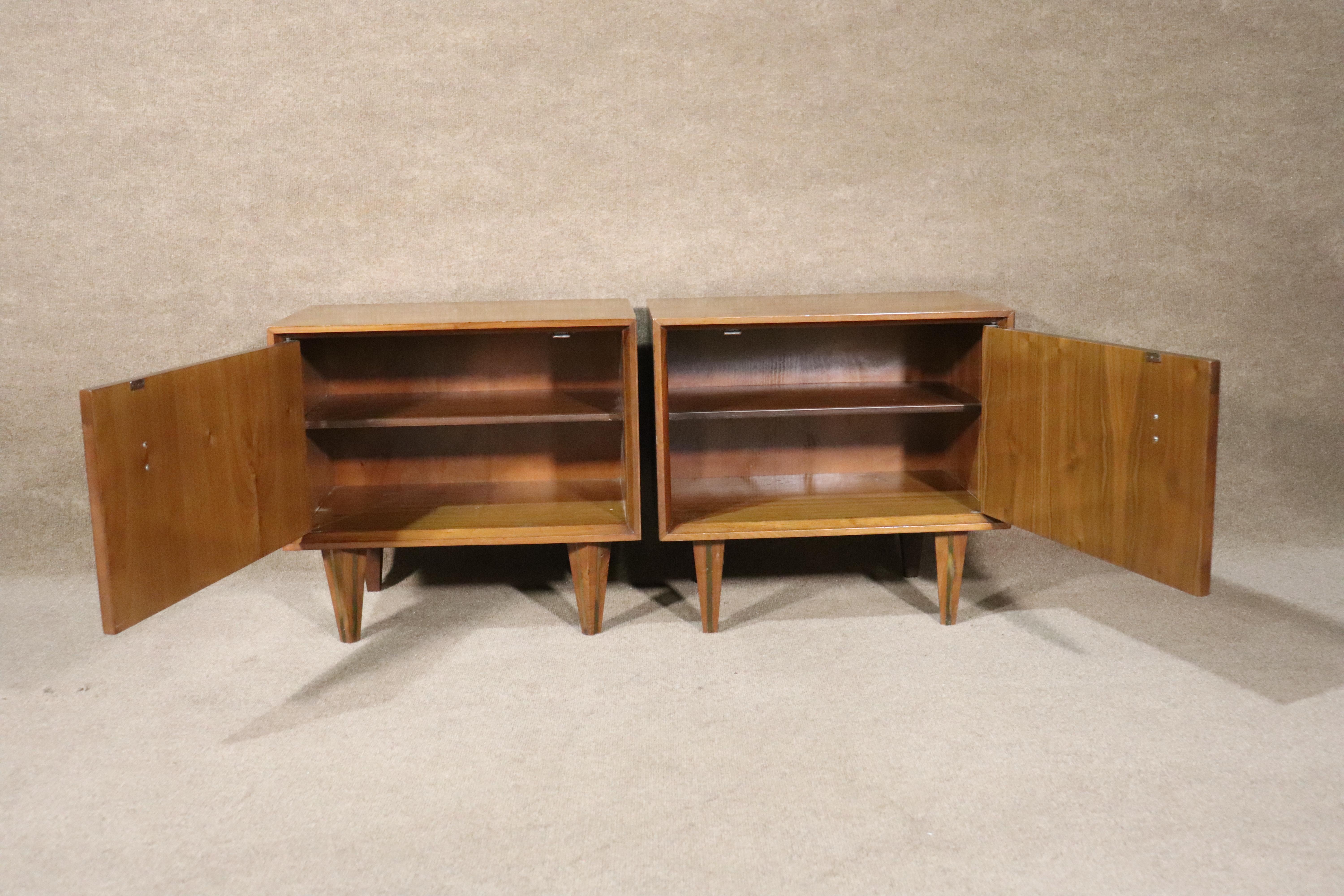 Pair of mid-century modern walnut tables with cabinet storage. Unique design with sculpted handles and brass inlay legs.
Please confirm location.