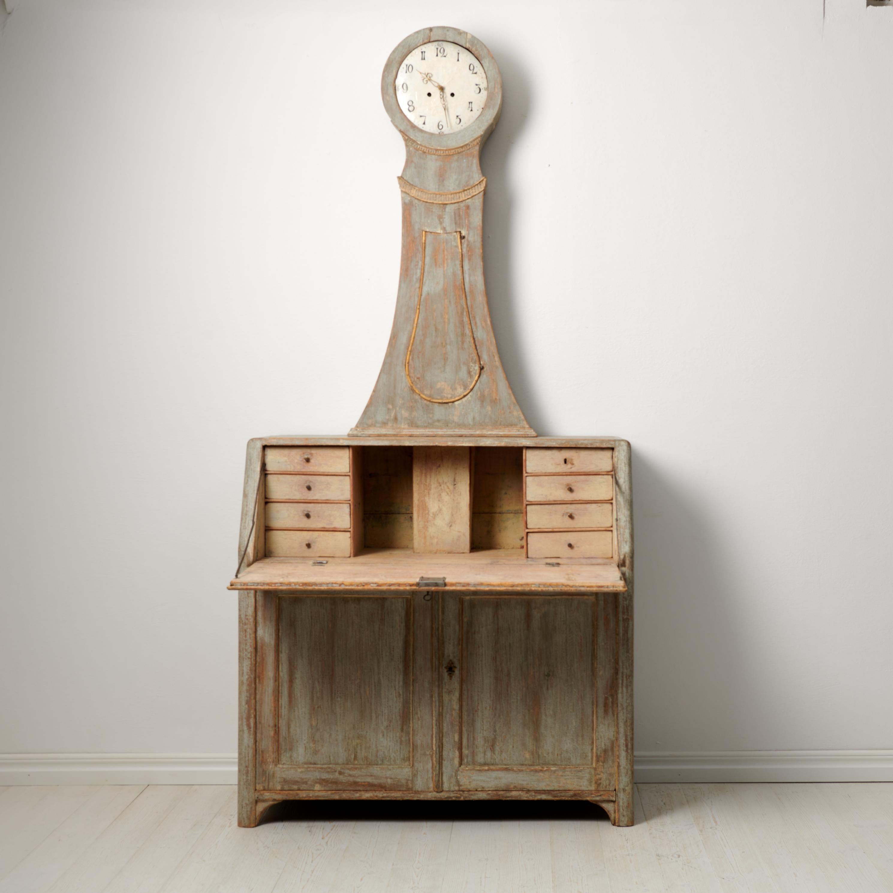 Seltener schwedischer antiker Uhrensekretär-Schreibtisch, hergestellt um 1820 bis 1840 in Nordschweden. Das Pult und der Korpus der Uhr sind von Hand aus massivem Kiefernholz gefertigt. Er verfügt über eine aufklappbare Tischplatte und Schubladen im
