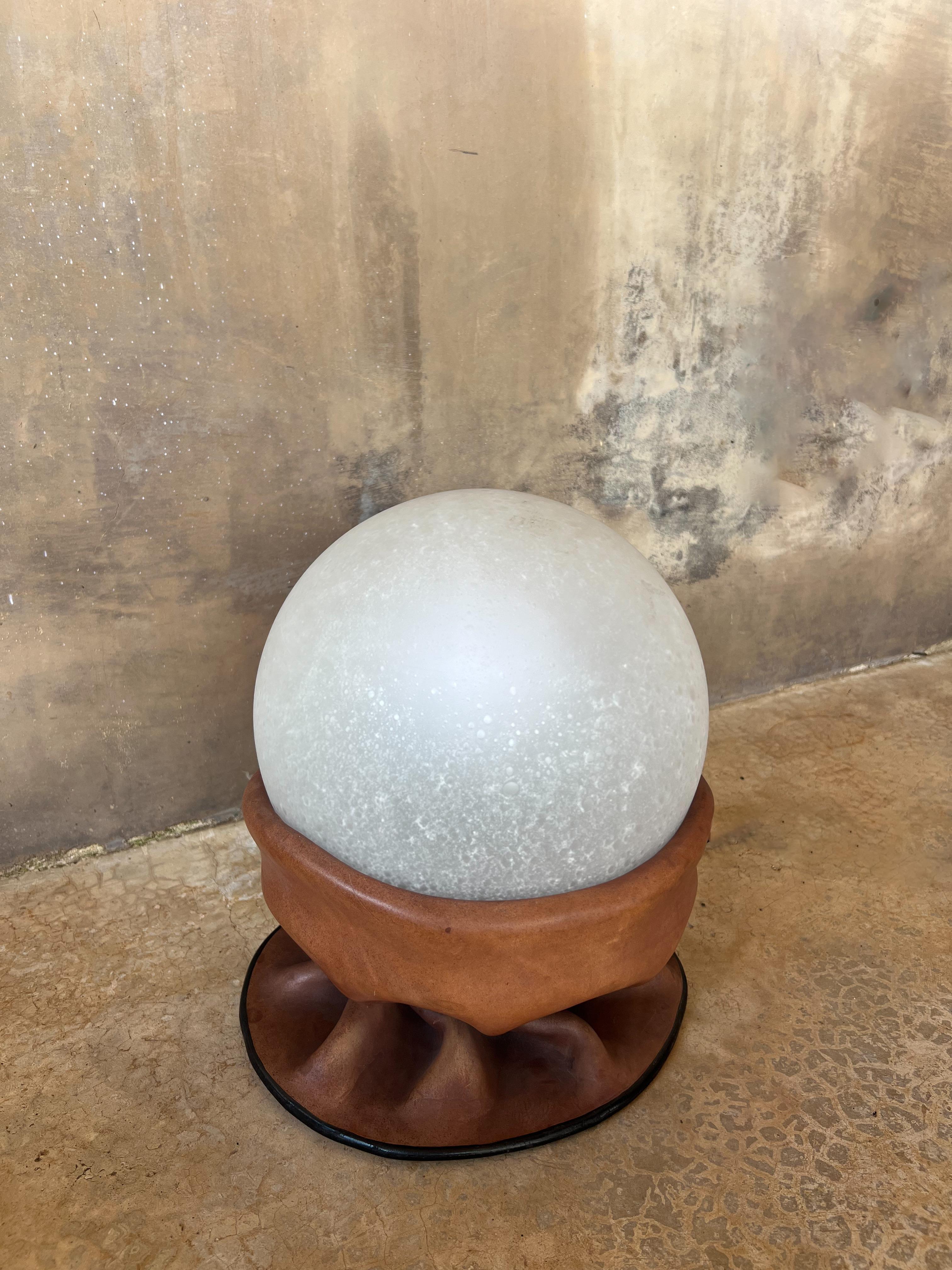 Una llamativa y poco común lámpara de sobremesa Nova Tecno, fabricada en Italia en la década de 1970. Esta pieza escultórica combina magistralmente cuero natural y cristal esmerilado, creando una cálida interacción de textura, forma y luz.

La