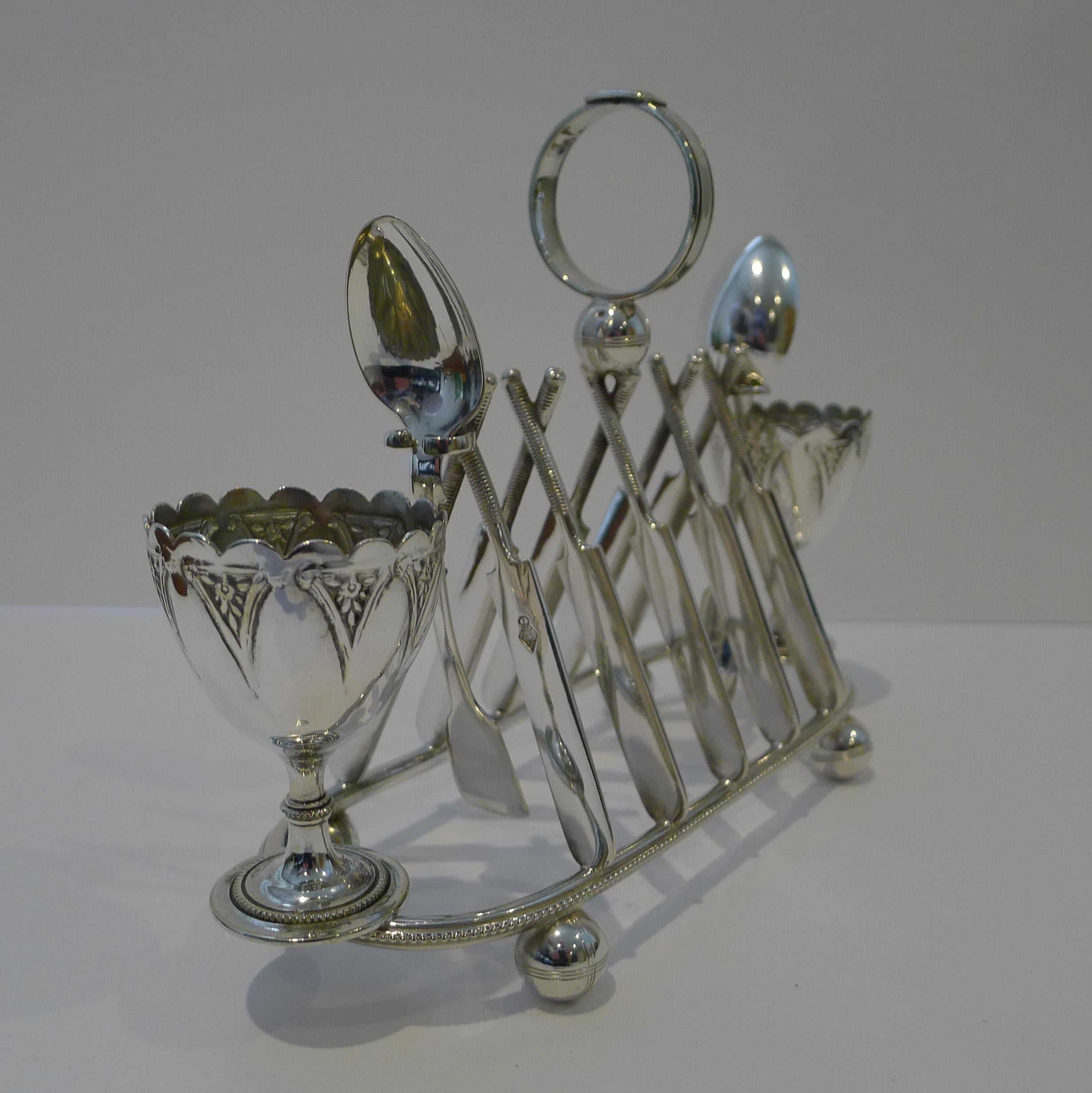 A rare find, this magnificent novelty toast rack / Egg Cruet of sporting interest, consists of the toast rack with an egg cup either end kept in place by an integral pin and two egg spoons; all in silver plate (EPNS).  The spoons are signed by the