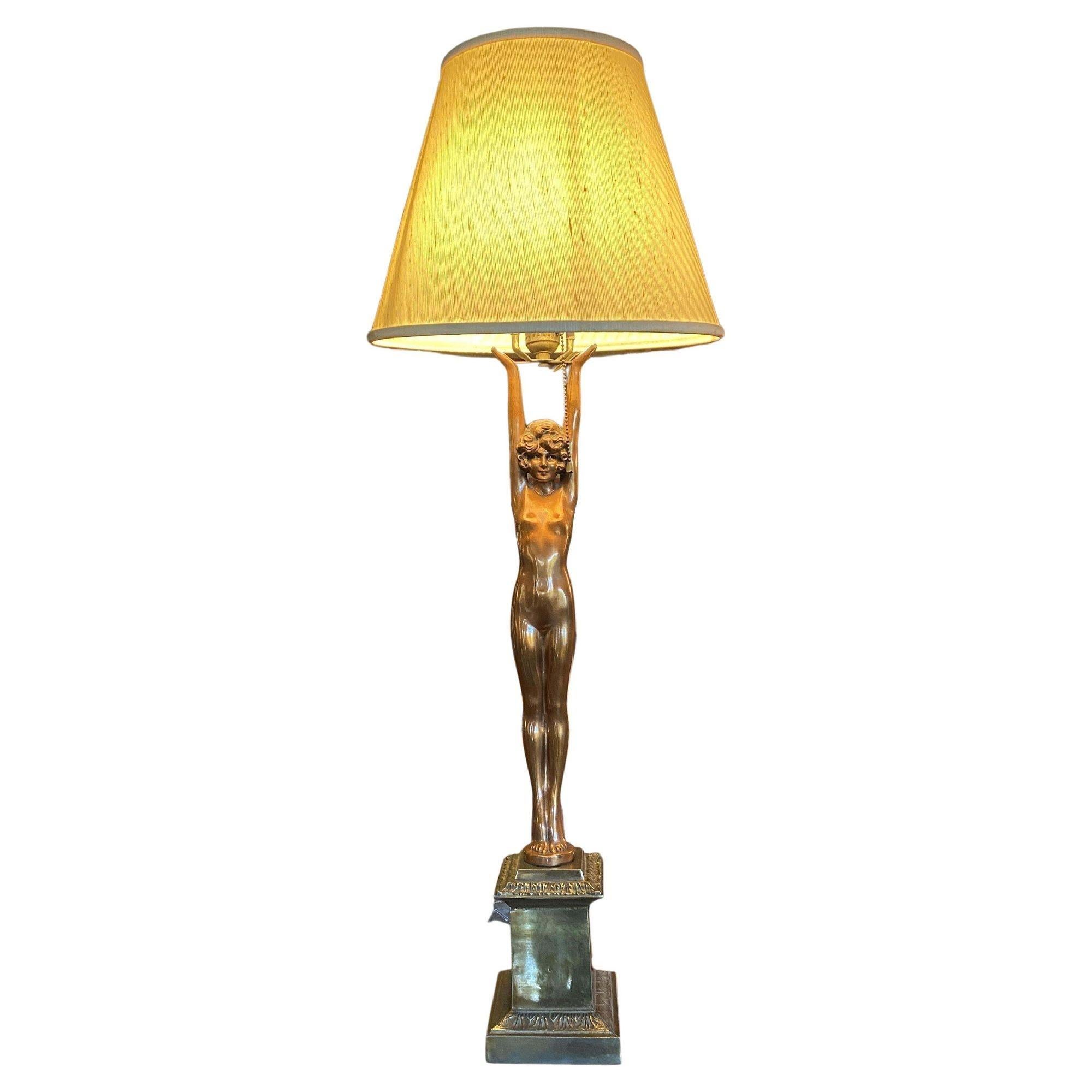 Rare Nuart table lamp pair, both featuring a nude bronze finished white metal female with outstretched arms holding up the light socket fixed a bronze column.
 
Made by Nuart Metal Creations company. 
 
Measures: Lamp 31