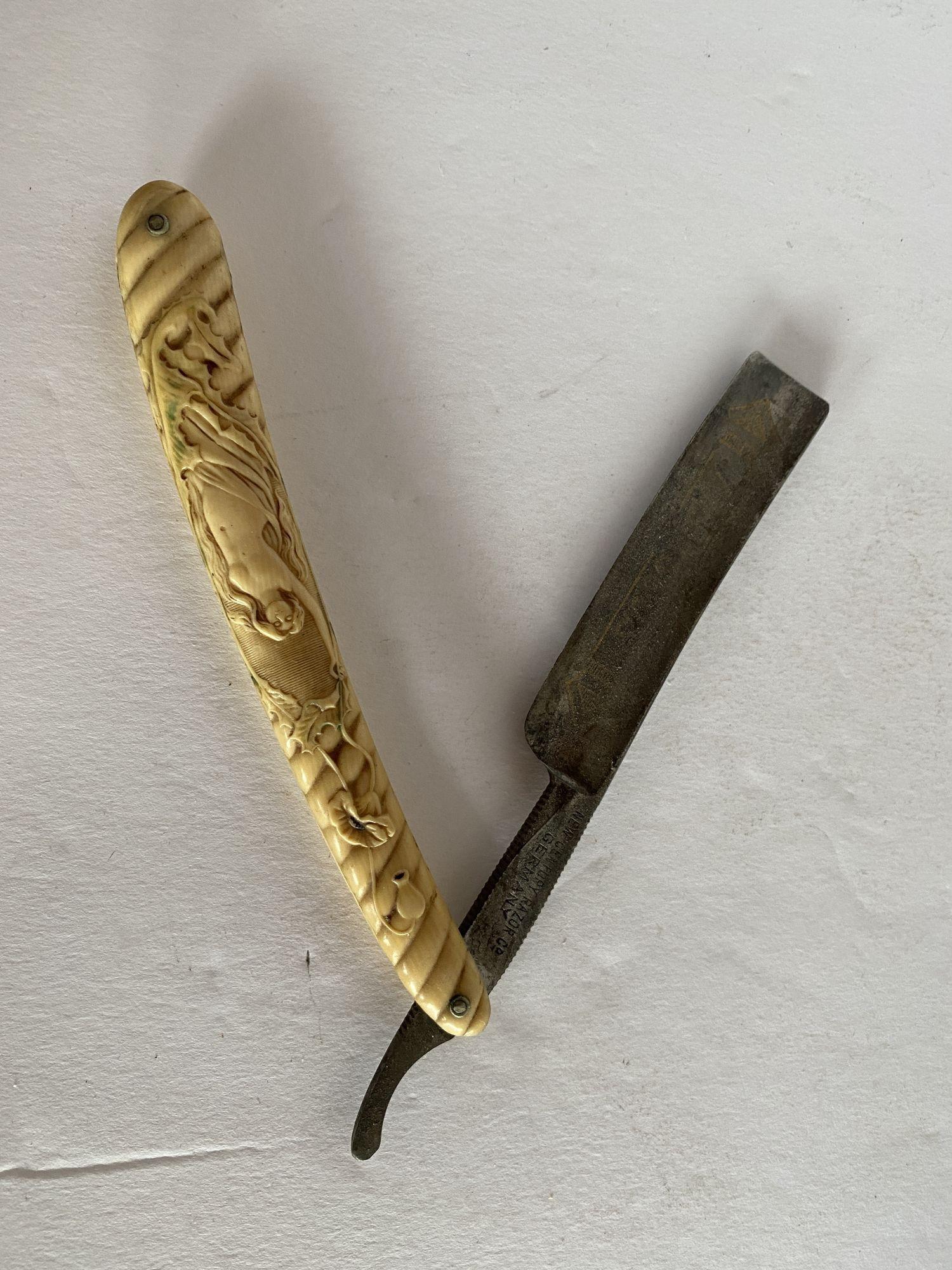 Raro rasoio nudo Art Nouveau con manico in celluloide. Si tratta di un grande rasoio dritto d'epoca con un dettagliato nudo Art Nouveau in piedi su una foglia di ninfea intagliata nel manico. È rimasta una parte della colorazione originale (verde),