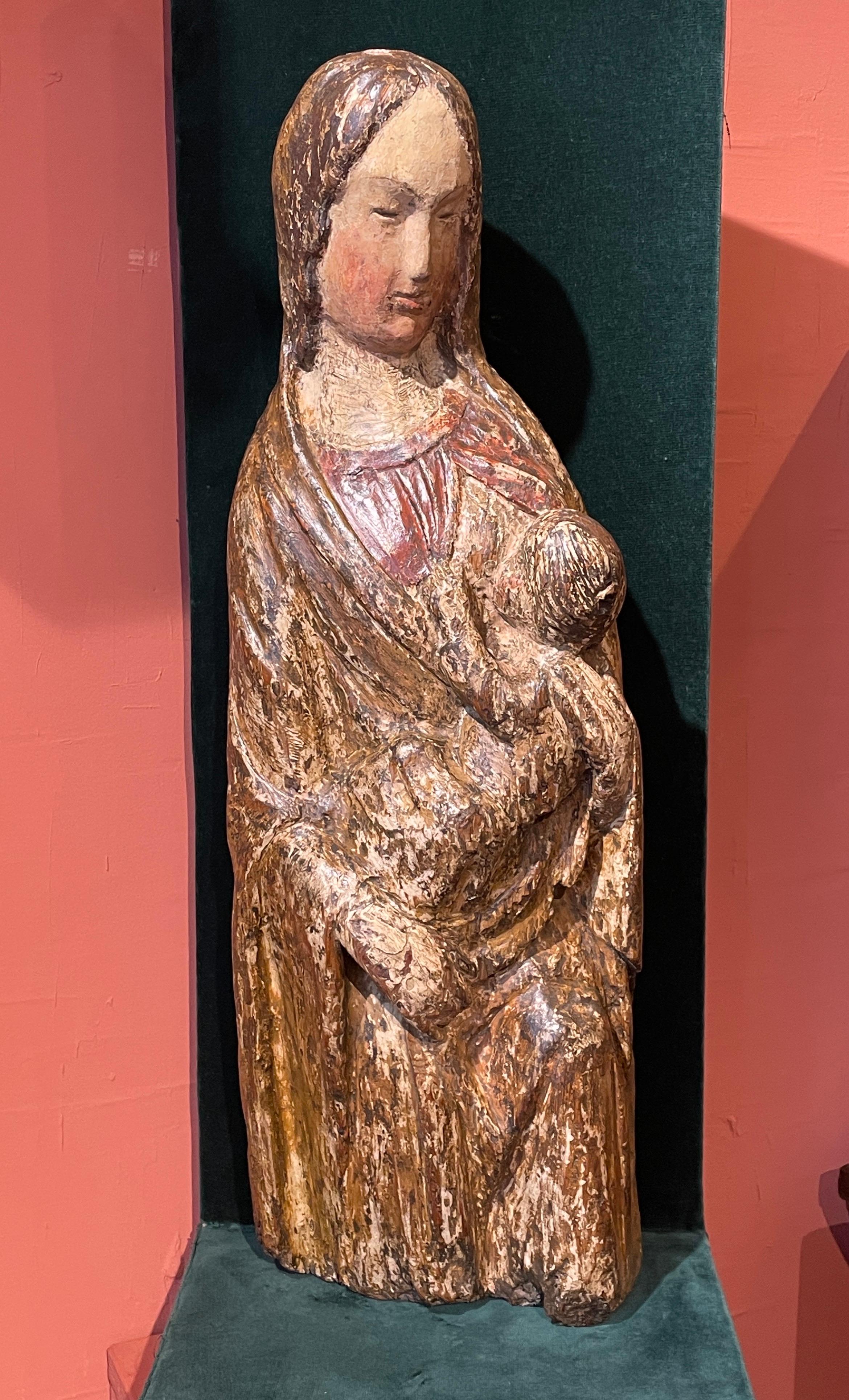 RARE NURSING VIRGIN FROM THE 14TH CENTURY

ORIGIN : ITALY
PERIOD : 14TH CENTURY

Height : 60  cm
Width : 20,5 cm
Depth : 11 cm
	
Wood 

Seated and in a very maternal position, Mary is wearing a red dress with a long, flowing cloak covering her