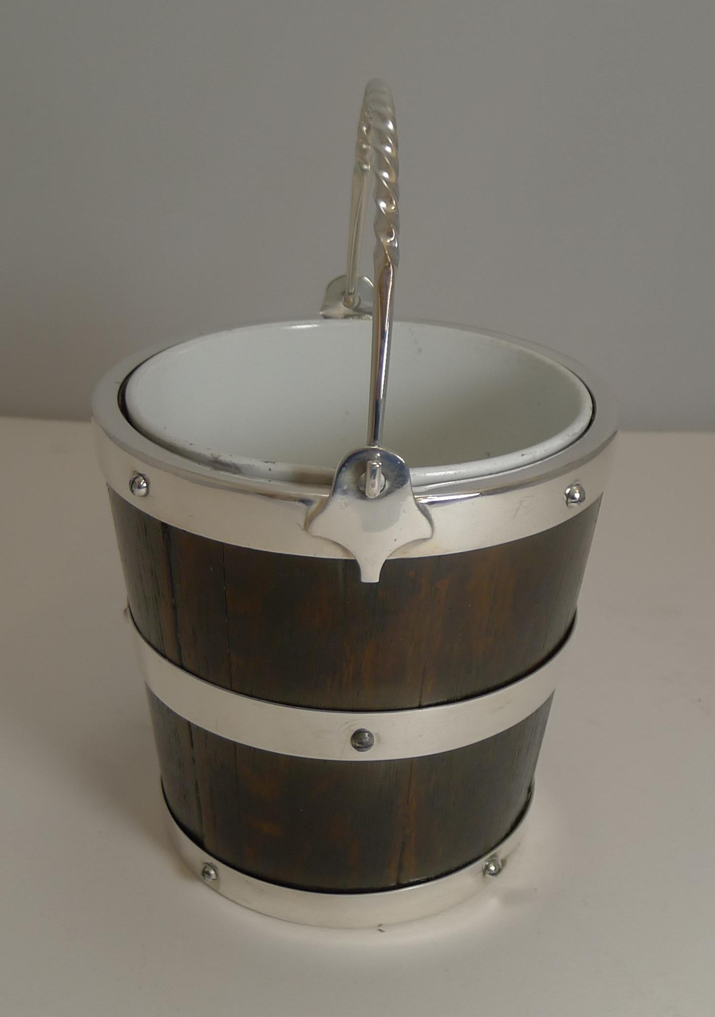Rarely found and highly sought-after ice bucket in English Oak in the form of a coopered bucket bound with silverplated banding with quality screwed construction.

The interior is lucky enough to have retained it's original creamware liner, and