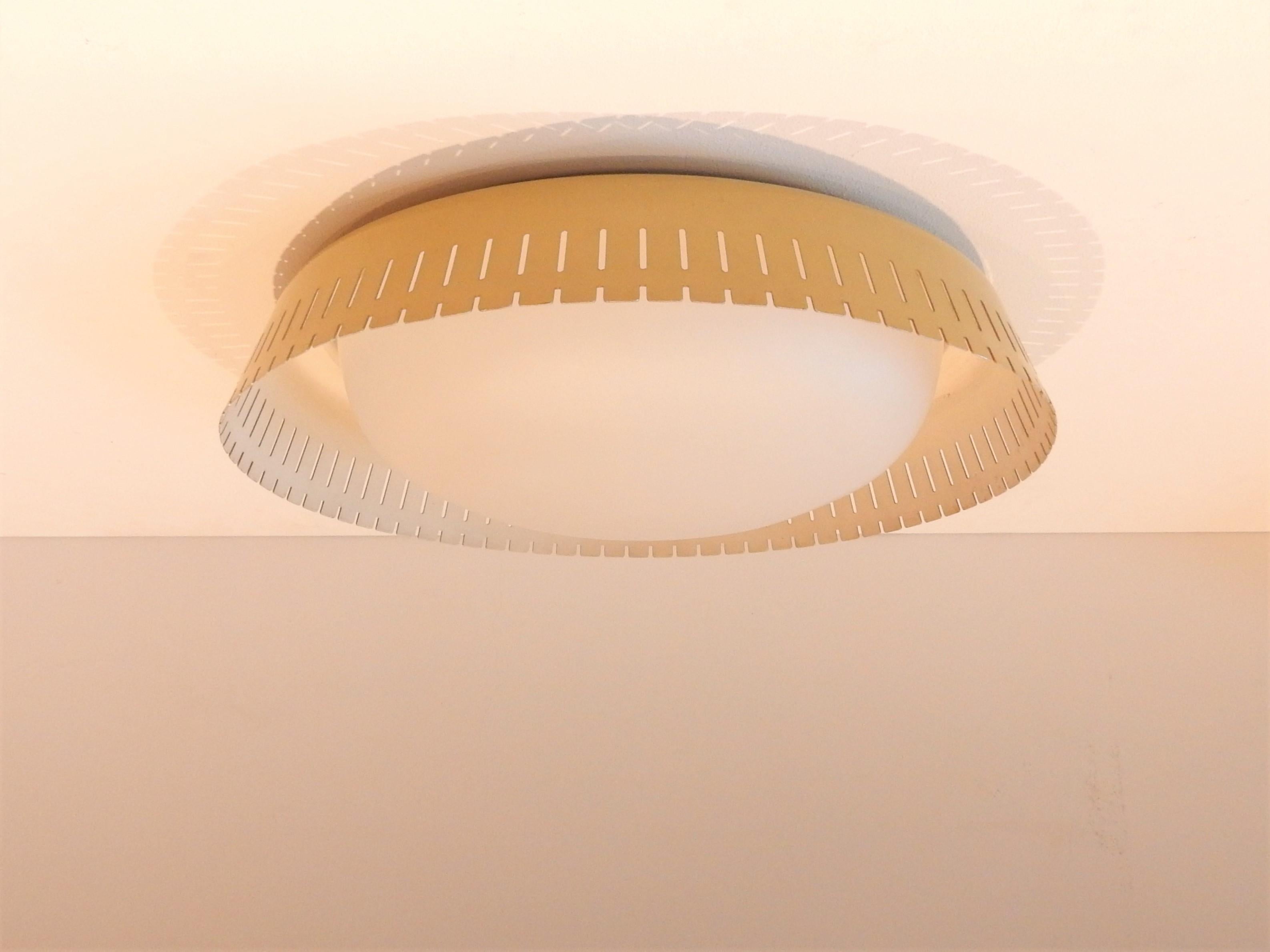 This ceiling lamp was designed by Bent Karlby in Denmark in the 1960s. A lamp that is not often seen. It is made of satin opaline glass surrounded by a yellow perforated metal edge that gives a beautiful and soft illumination. It has has 2 screw