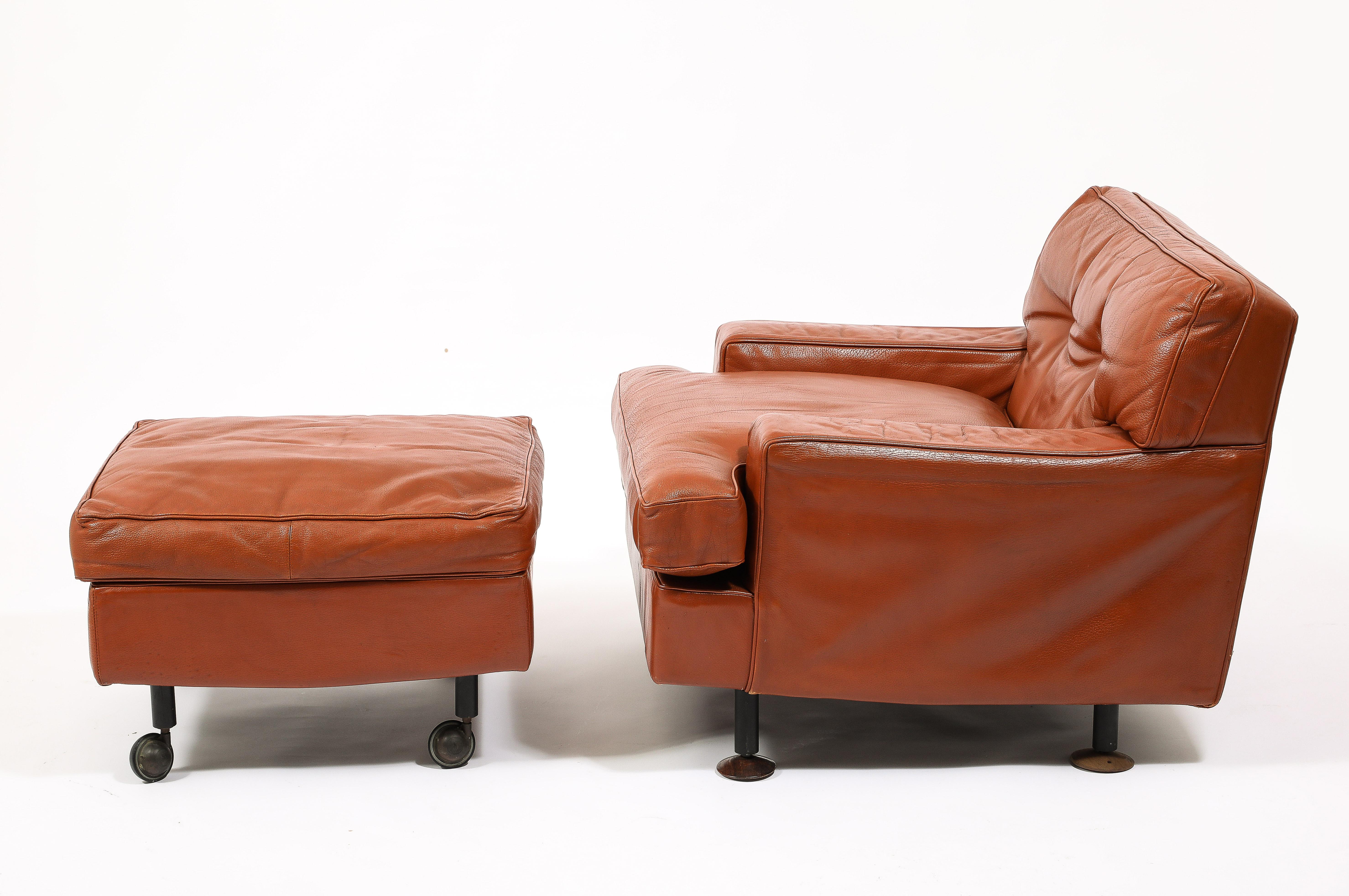 A rare set in its original leather, the leather has been professionally preserved by MHG studio while the interiors have been replaced or reinforced where needed. The chair is on adjustable feet while the matched ottoman is on casters for ease of