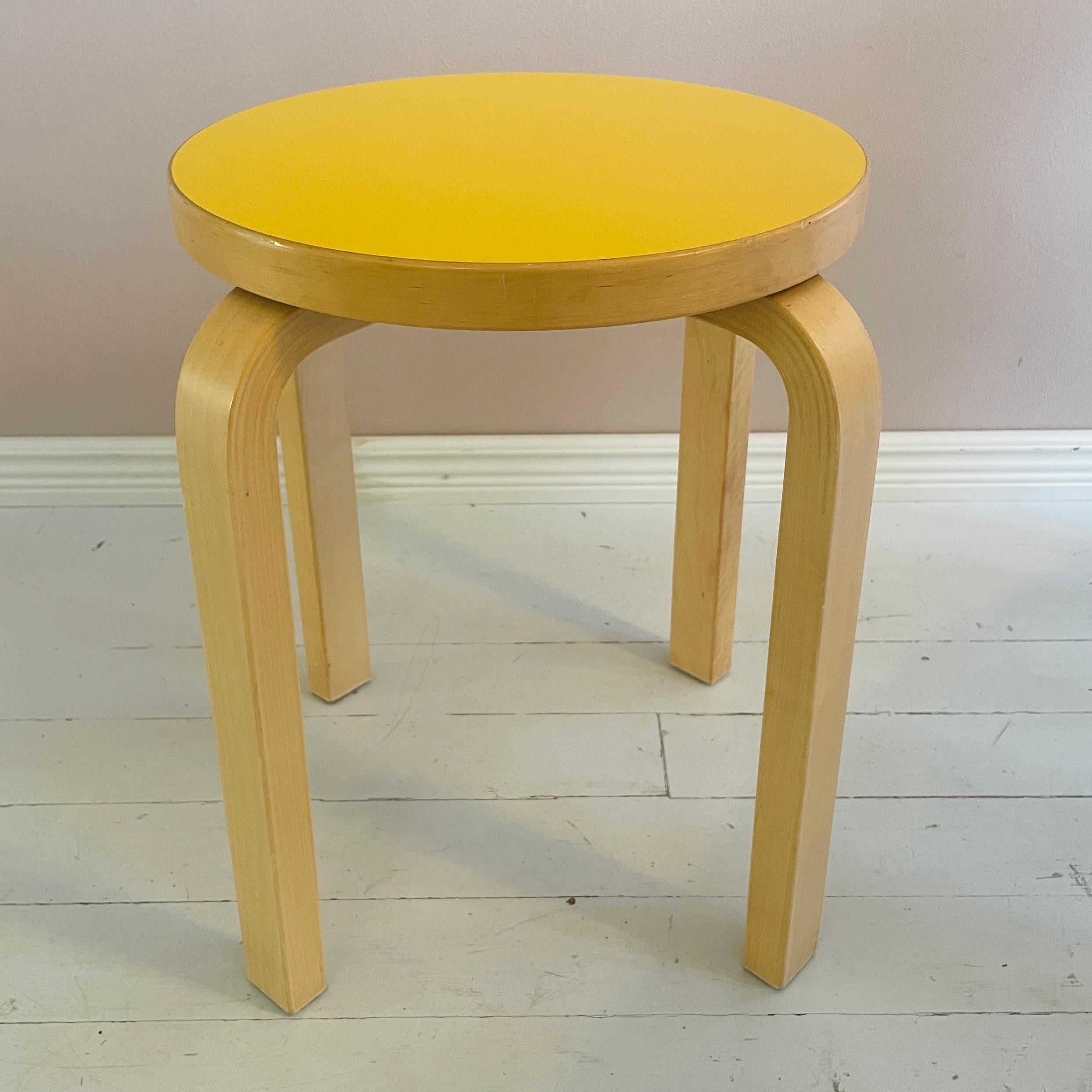 Tabouret E60 rare et de collection de l'architecte et designer finlandais Alvar Aalto, produit par Artek. Cette pièce emblématique est dotée d'une assise en stratifié jaune d'origine, une combinaison de couleurs abandonnée et très recherchée,