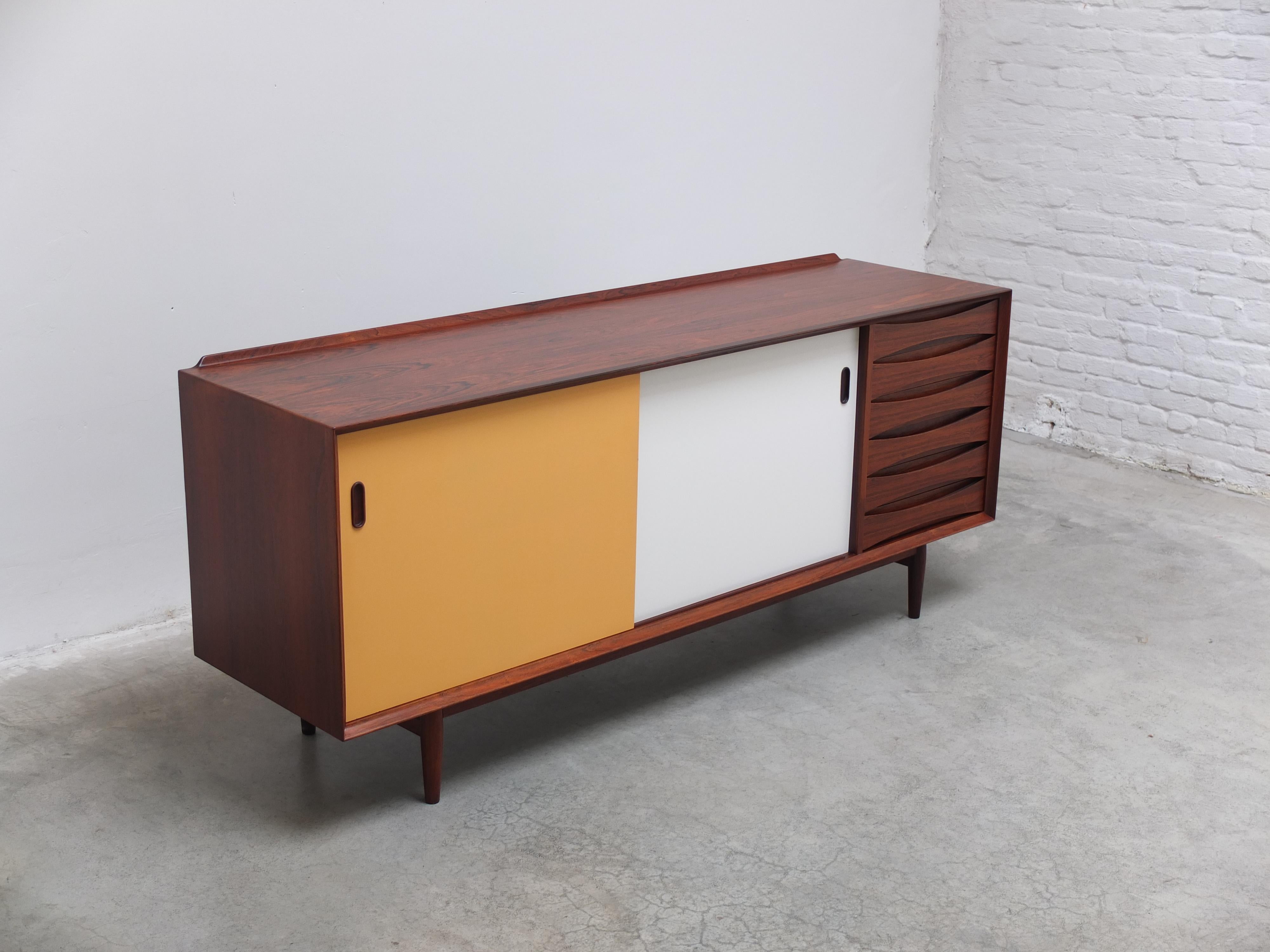 Iconica credenza modello 'OS29' o 'Triennale' disegnata da Arne Vodder nel 1959. Questa è la versione più rara e ricercata, con porte reversibili gialle e bianche, molto apprezzate e decorative. Dettagli fantastici come il bordo rialzato sul piano e