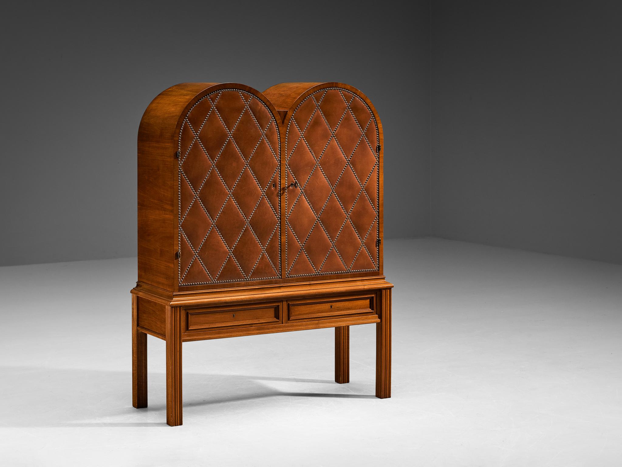 Otto Schulz, bar cabinet, walnut veneer, leather, brass, glass, Sweden, circa 1940.

This beautifully decorated bar piece was designed by Otto Schulz. It shows well-chosen proportions, with an open base and a well-sized bar unit placed on top. This