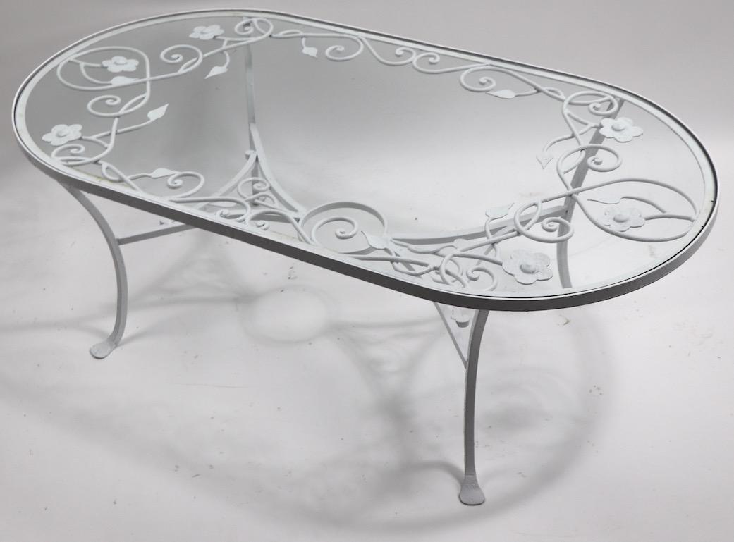 Oval coffee table by Salterini, hard to find and unusual form in wrought iron, with original glass top. Originally designed for outdoor use, also suitable for indoor application. Great quality decorative foliate iron, clean and ready to use