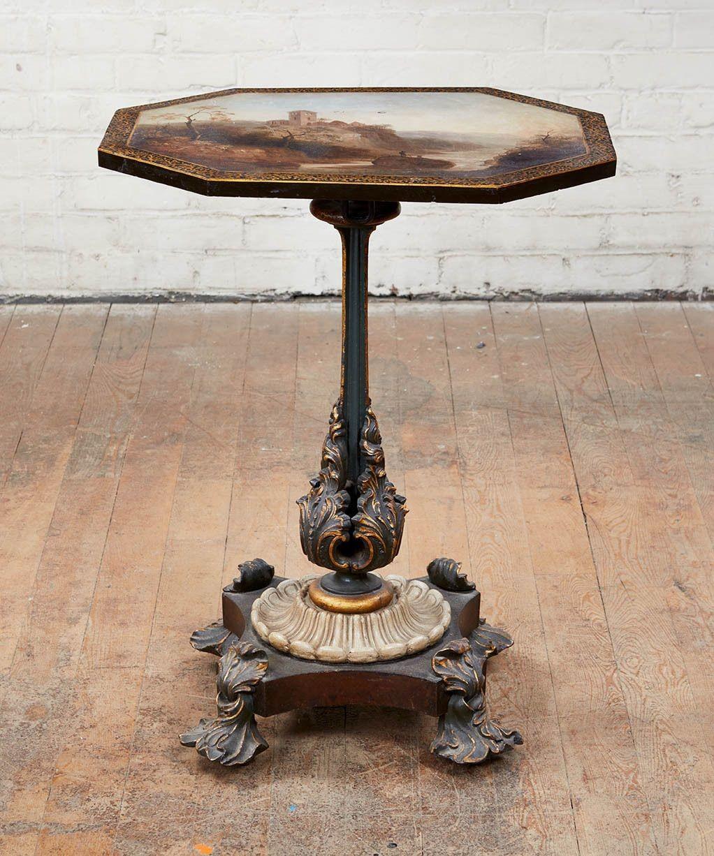 Fine and unusual English mid-19th century cast iron octagonal tilt top table, the top with painted landscape depicting two fishermen on a rock in a river with ruined abbey in the background, possibly after Edwin Landseer, with gilt seaweed border,