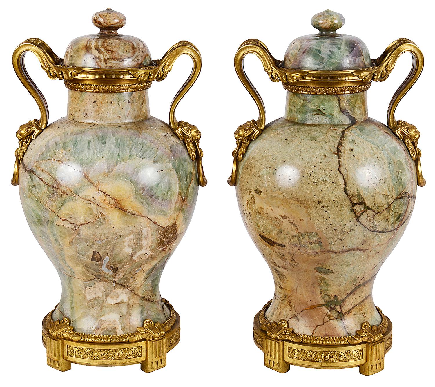 Rara e importante coppia di vasi con coperchio in quarzo della fine del XVIII secolo, ciascuno con splendide montature e manici classici dorati in ormolu a volute, terminanti con teste di leone, artigli e gocce ad anello. Innalzate su basi circolari