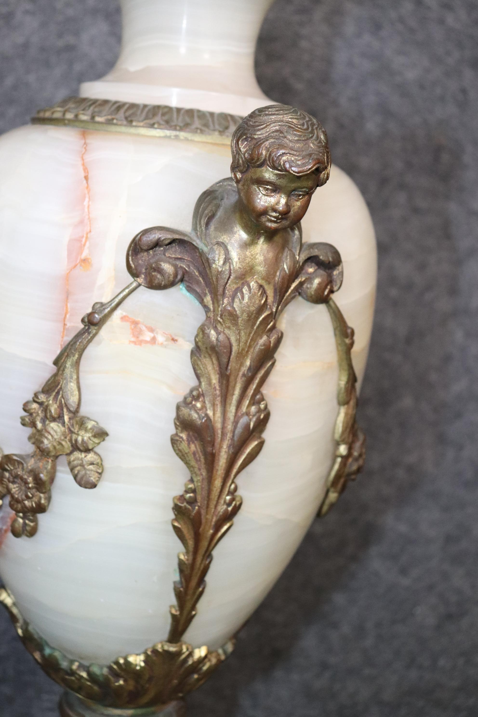 This is a beautiful pair of white translucent onyx cassolettes. They are adorned with the bronze putti or cherubs and floral wreathes. They date to the 1880-90s era and are in good condition with normal age related signs of wear and use. They