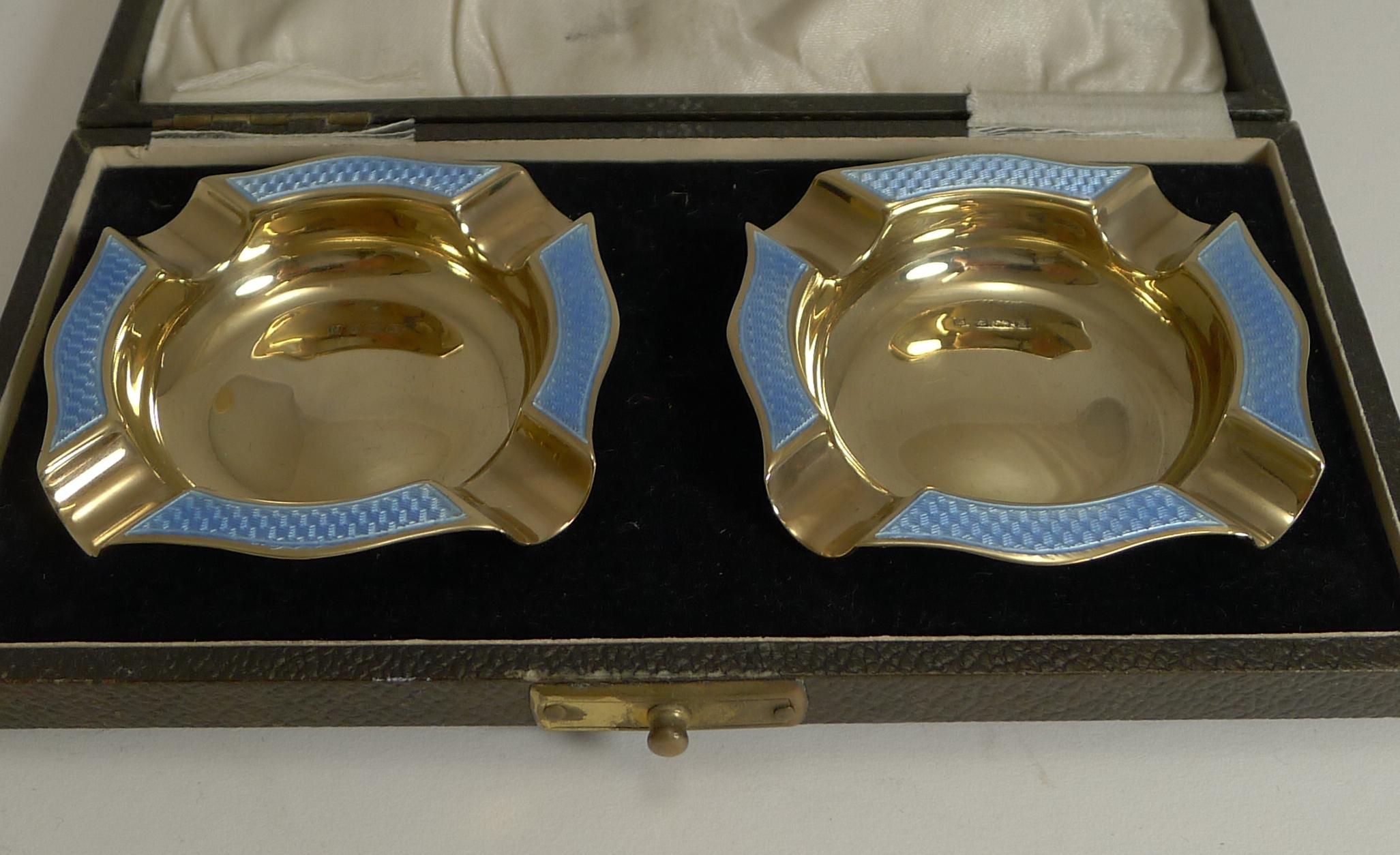 A magnificent and very glamorous pair of English sterling silver, gilt (gold on sterling silver) ashtrays decorated with a stunning blue guilloche enamel without damage.

Each is fully hallmarked for Birmingham 1929 together with the makers mark