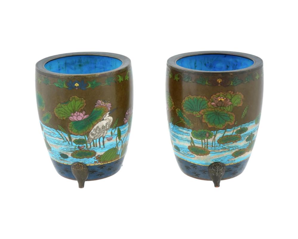 Un par de raras macetas antiguas japonesas, de finales de la era Meiji, esmaltadas sobre cobre. Las macetas están esmaltadas con diseños policromos que representan escenas con garzas en un estanque con flores en flor y estanques realizados con la