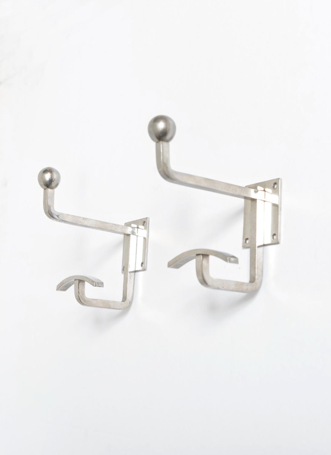 This rare pair of Mid-Century nickel-plated coat hooks by avant-garde French designer Jean Royère are incredibly stylish and functional. Born in Paris, Jean Royère (1902-1981) made an international reputation as designer of luxury interiors in