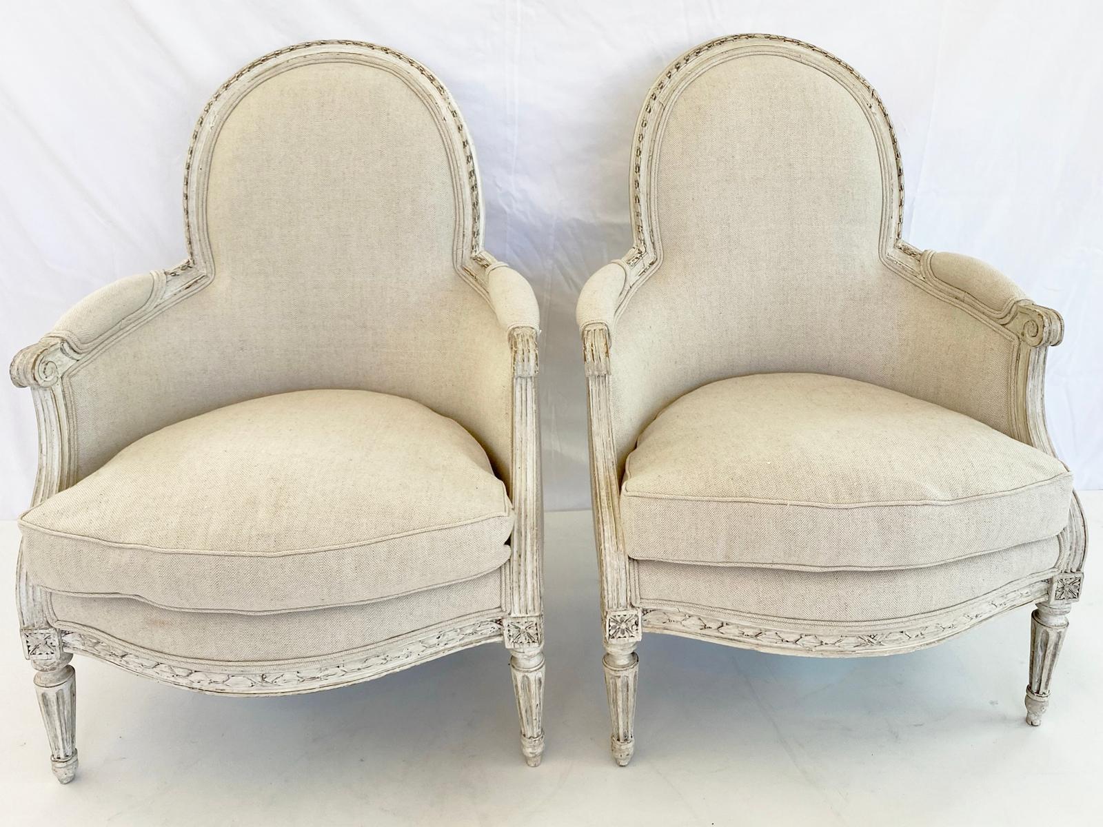 An important pair of period child's berge`re chairs, of painted walnut; each oval padded backrest in gadrooned frame, outswept arms with padded elbow rests on reeded splayed terminals, loose drop-in cushion on bowed seatrail carved with