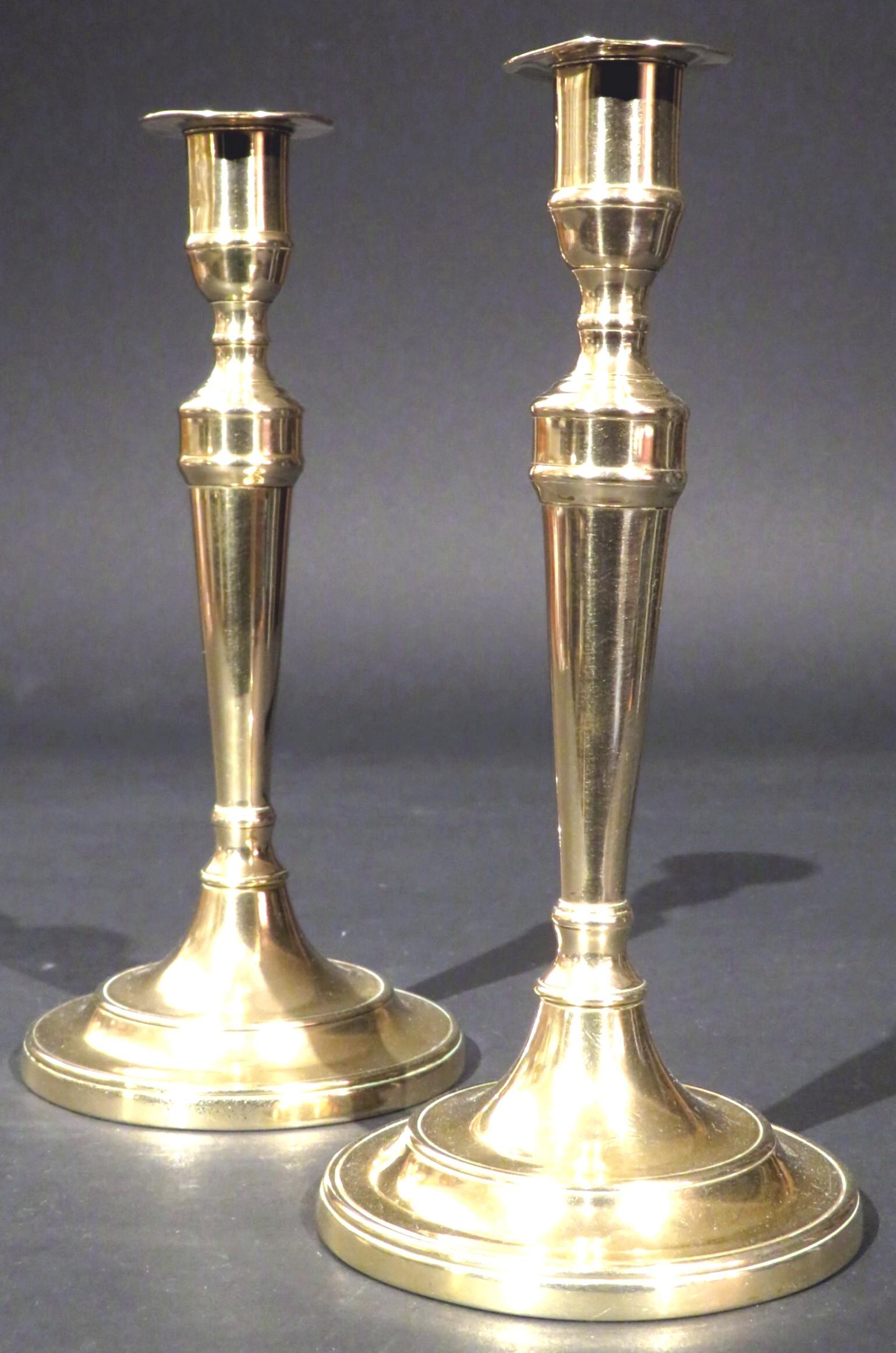 Ein sehr hübsches und seltenes Paar Glockenmetall-Leuchter aus dem 18. Jahrhundert, beide mit aufgeweiteten, gesäumten Säulen mit zylindrischen Tüllen und abgeflachten Tropfschalen, die sich auf abgestuften runden Sockeln erheben, die ihre