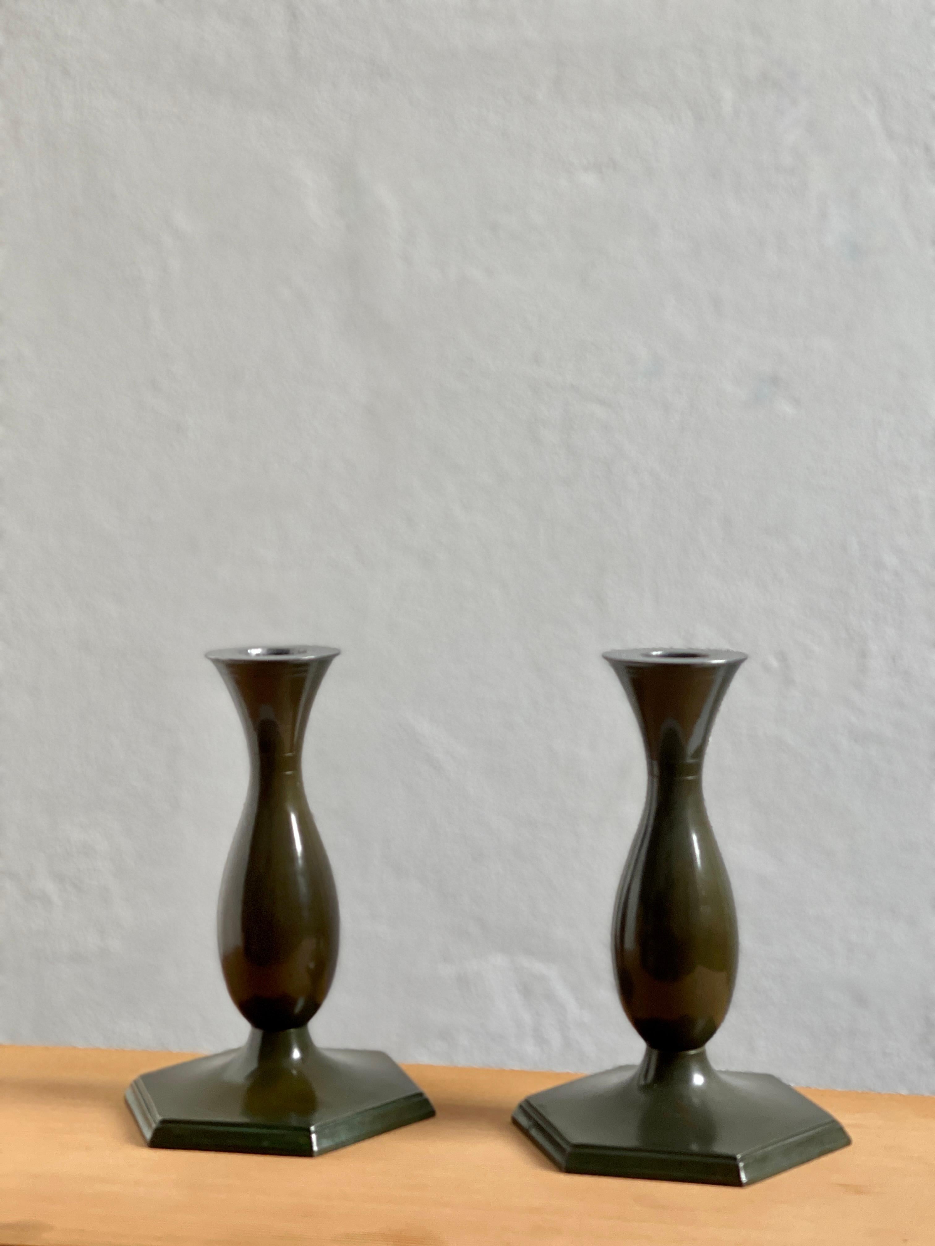 Diese exquisiten Kerzenhalter sind der Inbegriff der Eleganz des Art Déco der 1920er Jahre und wurden von den geschickten Händen des dänischen Metallarbeiters Just Andersen gefertigt. Als Zeugnis der Faszination der Epoche für geometrische Formen