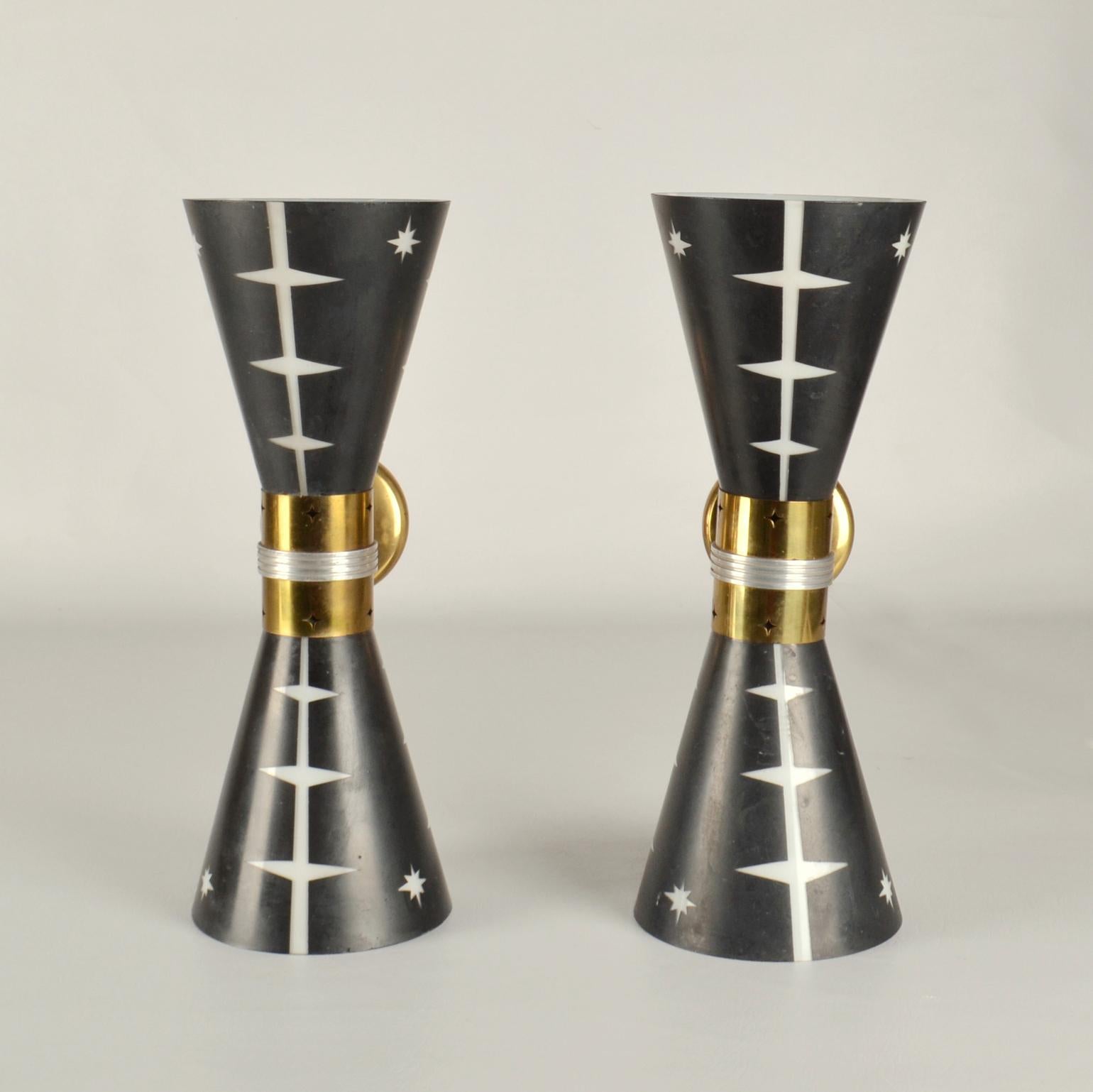 Unique large hourglass wall sconces are designed with up and down light from the conical blown glass shades in opal glass with an  outer body layer of black glass that is etched on the outside to reveal a star shape pattern that illuminates its