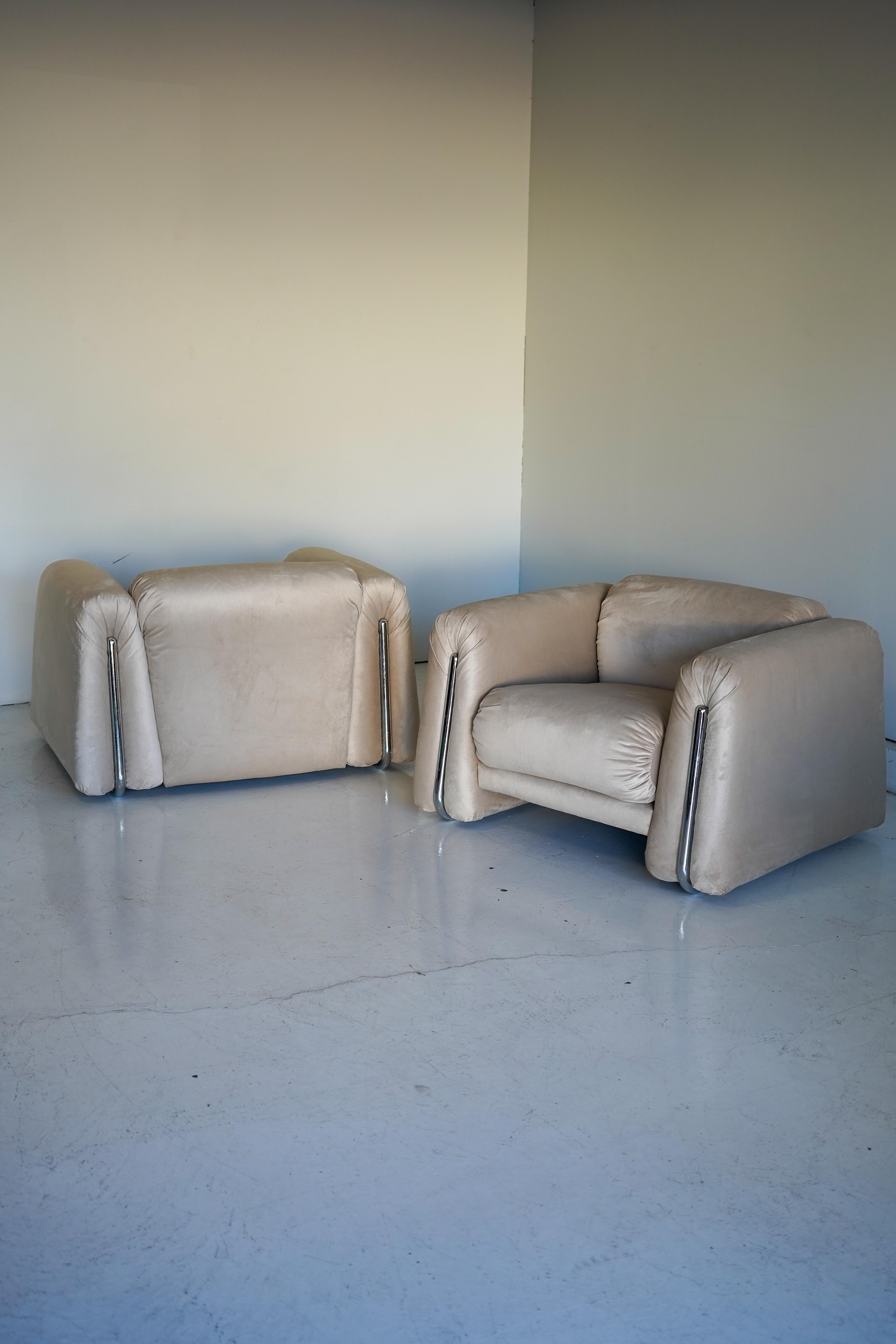 Rare and unique pair of chrome-wrapped Italian armchairs. Soft, geometric shapes with a commanding presence and reupholstered in a soft and smooth champagne velvet. 

In excellent condition. Sold as a pair.