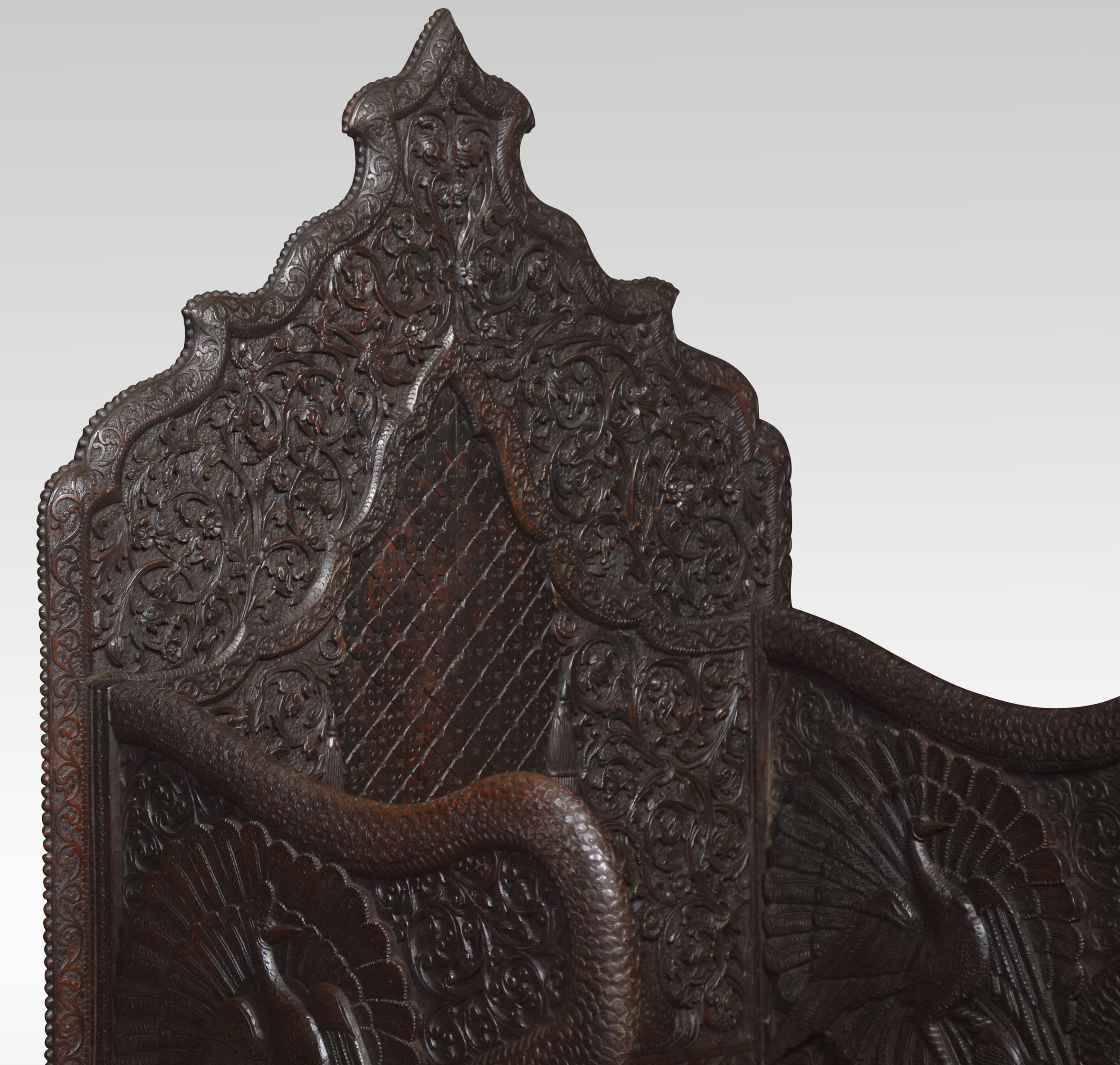Rare pair of 19th-century carved ceremonial armchairs, the profusely carved backs with flower heads and scrolling leaf decoration to the lift-up seat retaining the original locks. Flanked by crisply carved peacock arms. Above further decorative
