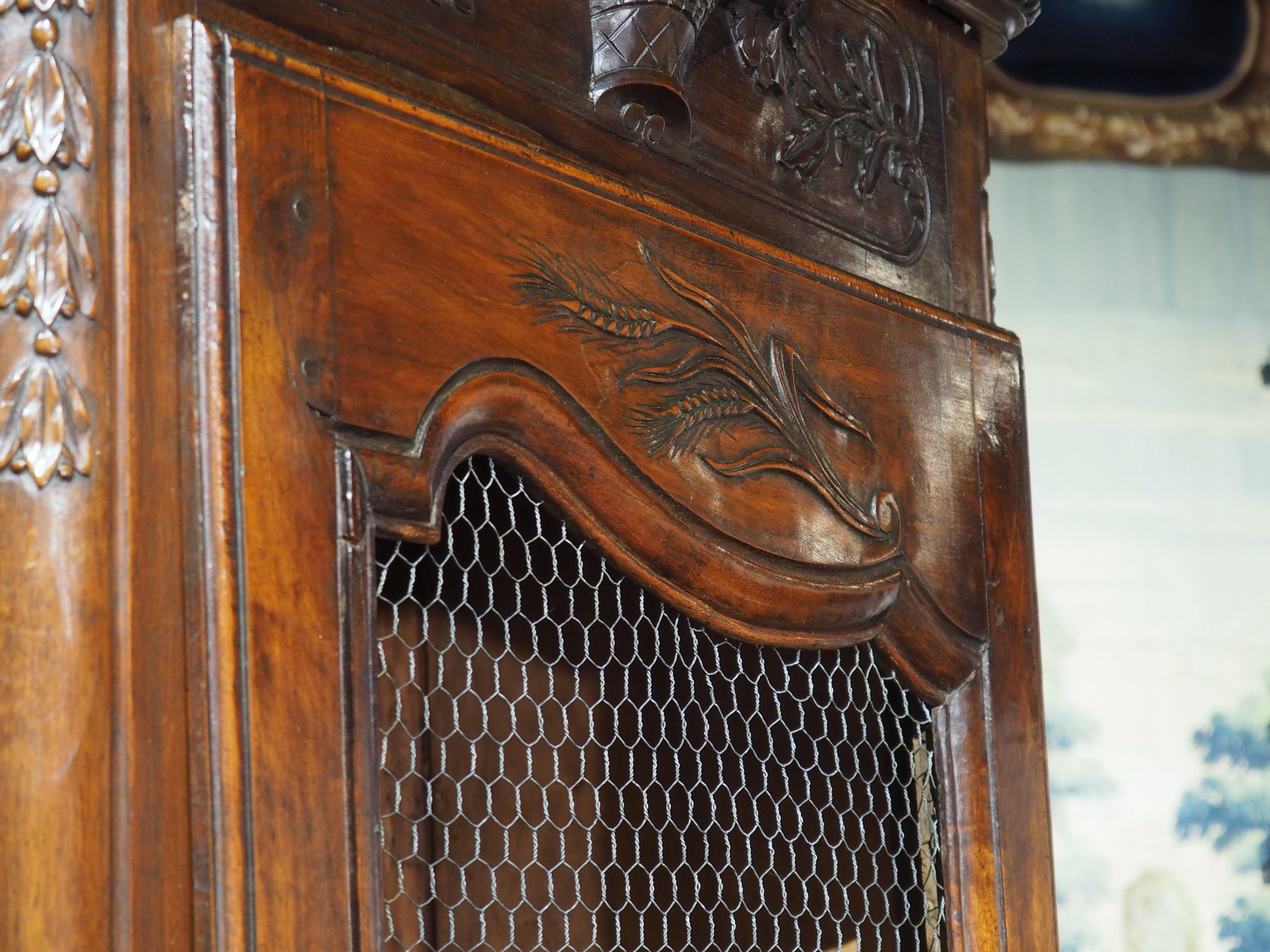 From Provence, France, this rare pair of bonnetieres was hand-carved in walnut wood in the 1800’s. A bonnetiere is a tall and narrow storage cabinet, like an armoire, but typically smaller and with one door. Typically found in the entrances of