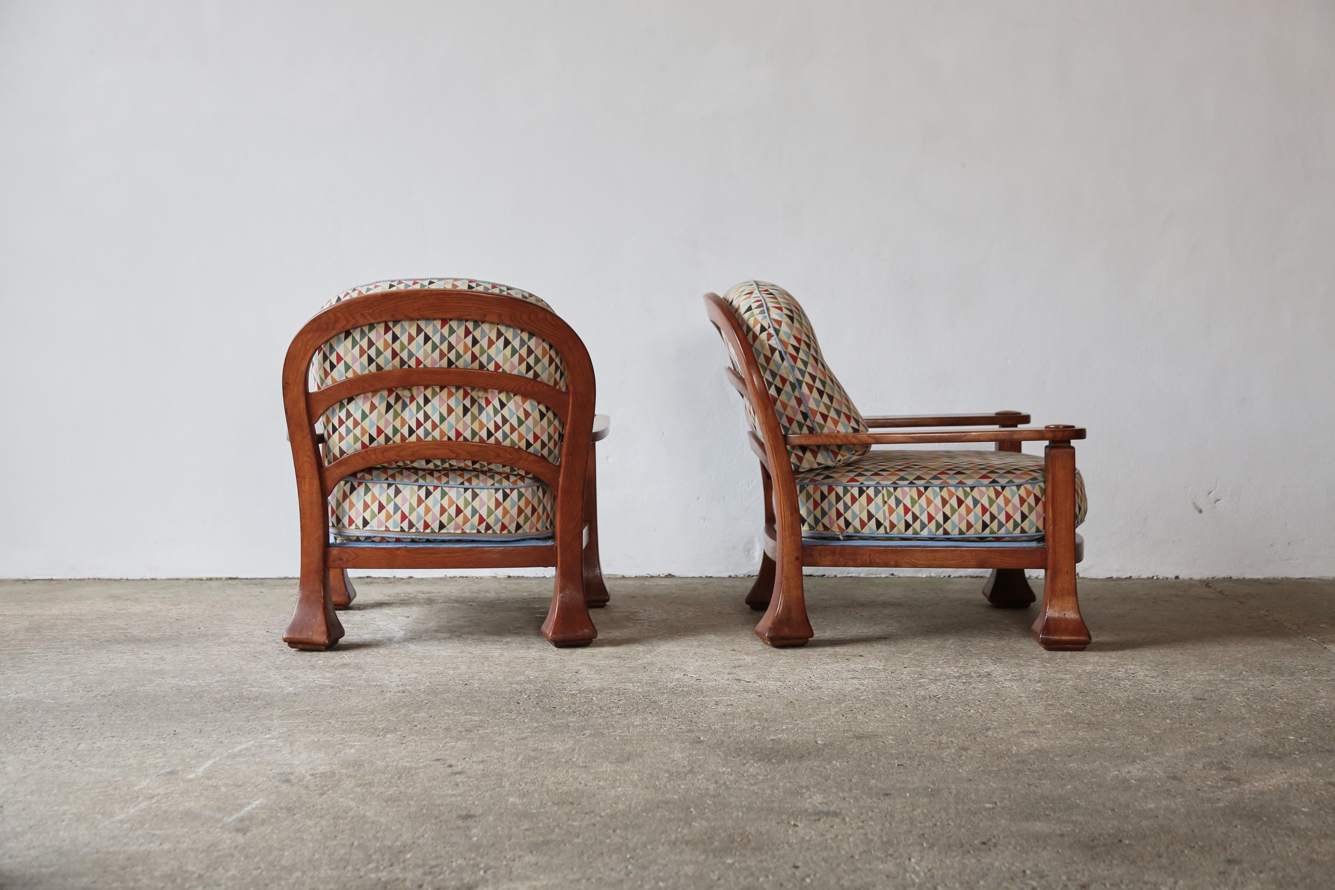 A rare and unusual pair of Italian 1970s armchairs. The loose cushions are recently recovered in a colourful geomatric pattern, but are easy to recover if a different fabric is preferred. The wooden frames have a good even tone and patina and are in