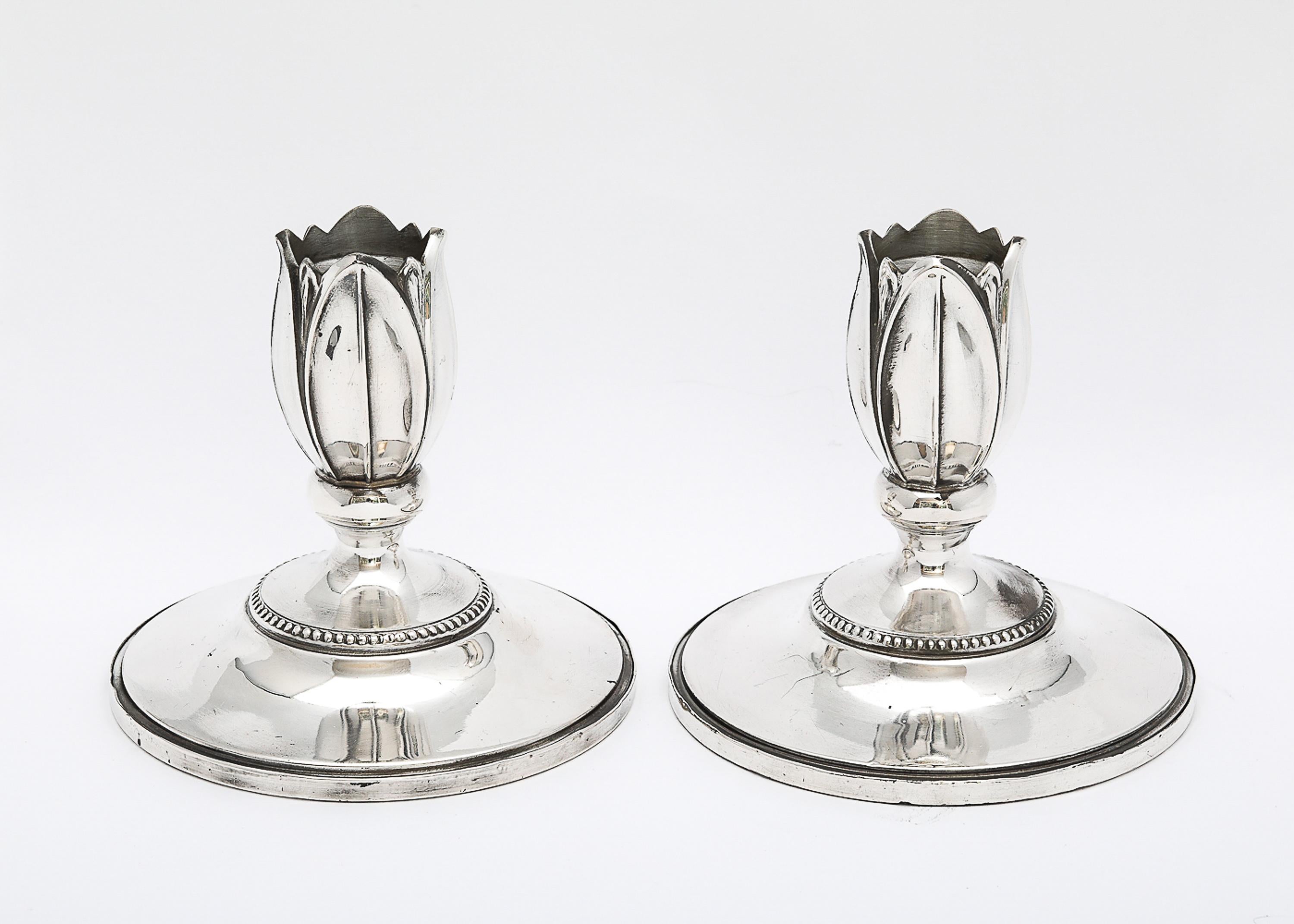 Rare pair of Art Nouveau-Style, sterling silver candlesticks, Fisher Silver Co., Jersey City, New Jersey, Ca. 1935. Beautifully and gracefully designed, each candlestick is designed to be a flower emerging from the base of the candlestick. 
Each