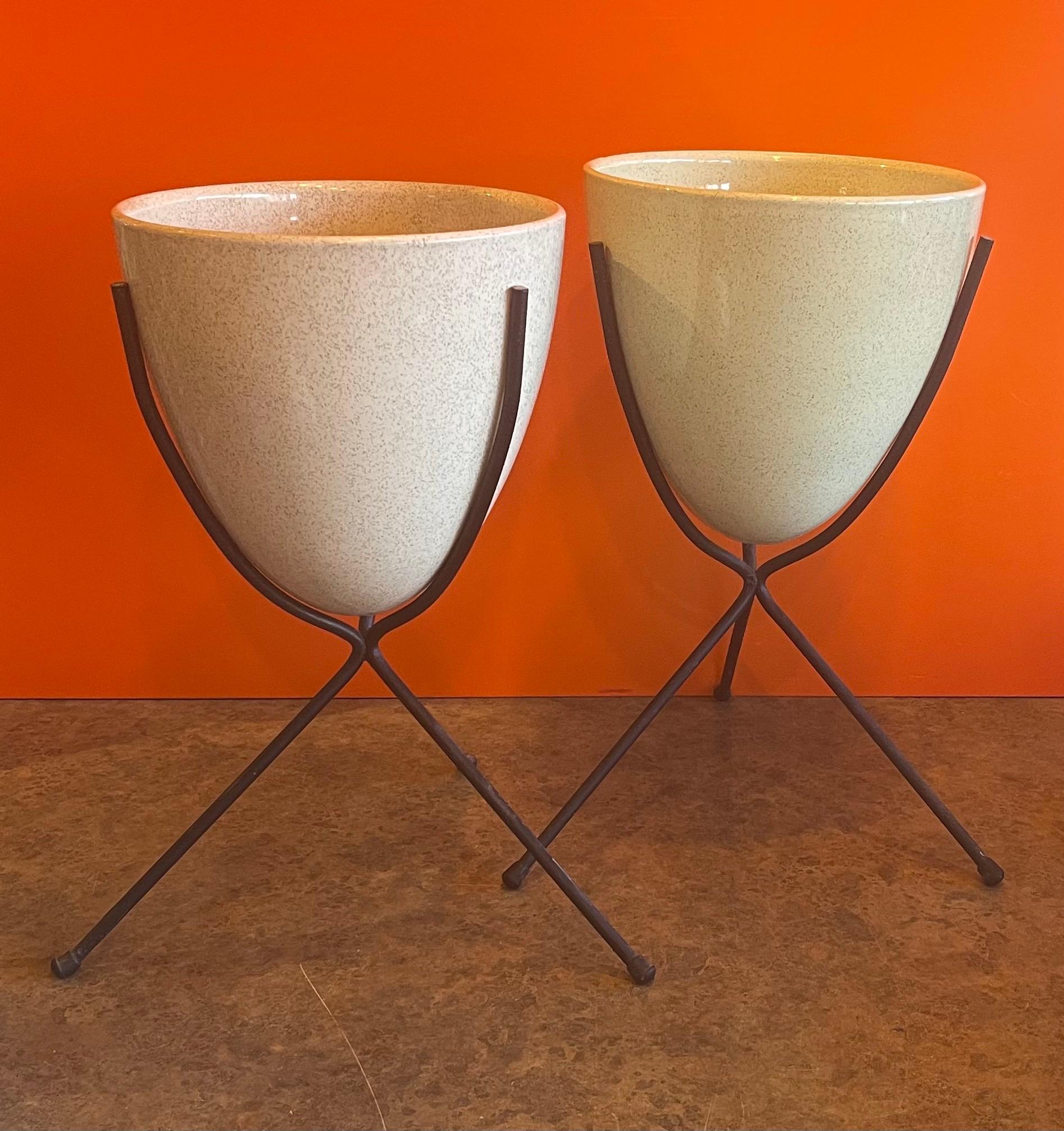 Rare pair of atomic age ceramic bullet planters with iron bases by Bauer, circa 1950's. The pair are in very good vintage condition with no chips or cracks (some oxidation on the inside from dirt). Both planters have a 