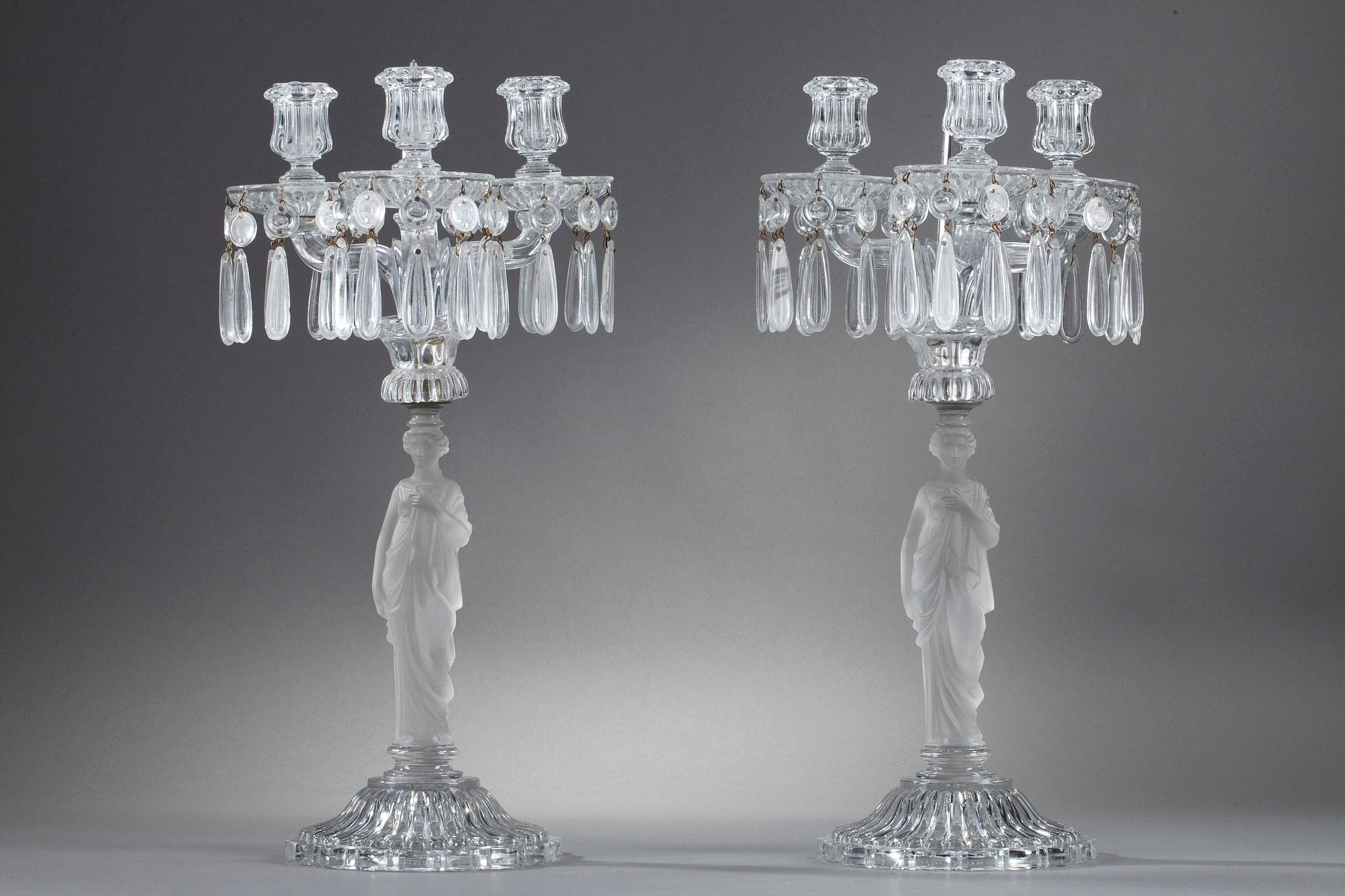 Pair of candelabras in molded and satin-finished crystal from Baccarat, featuring caryatids on which rest three arms of light decorated with crystal pendants. The central shaft in satin-finish crystal is sculpted with draped caryatids with