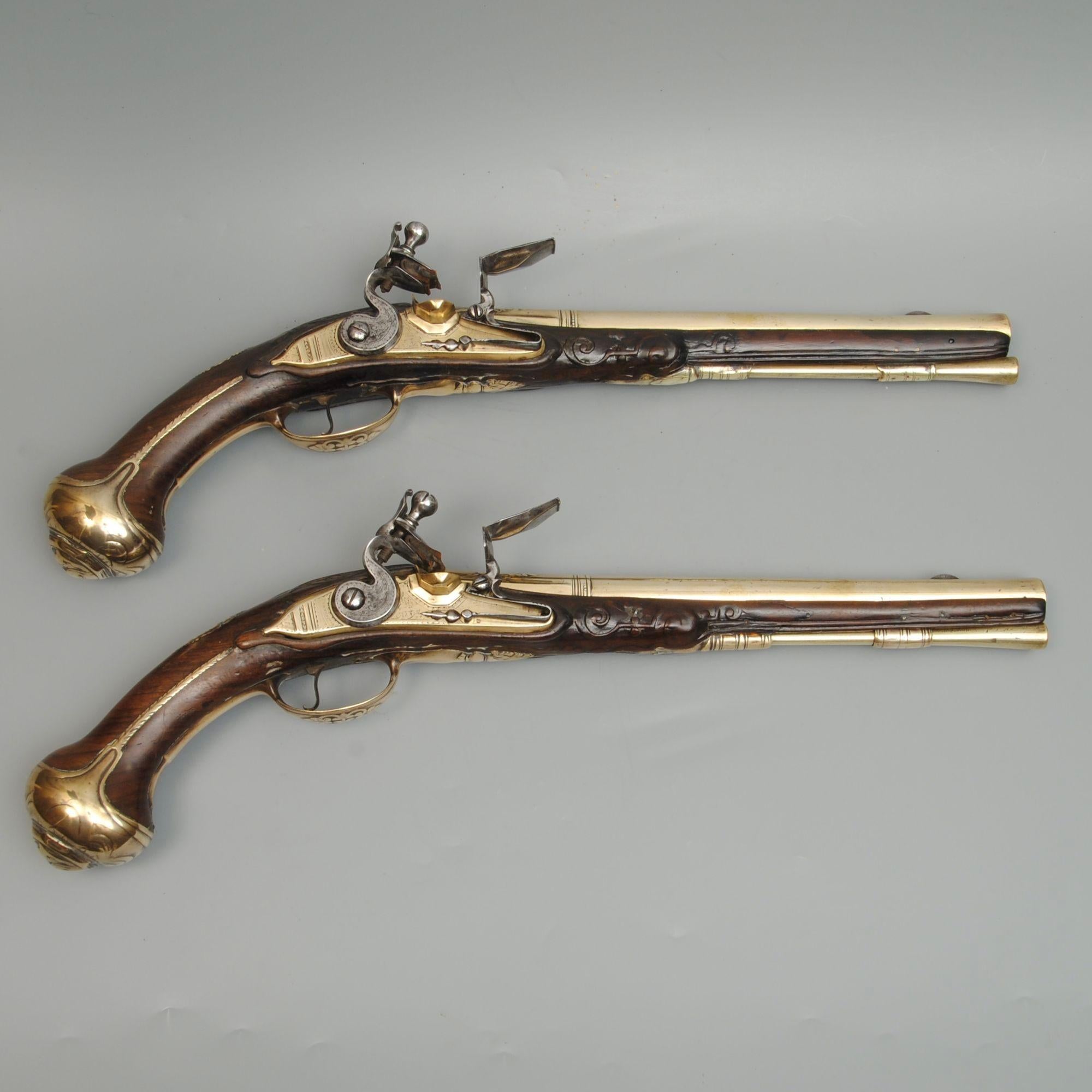A fine and rare pair of brass mounted flintlock pistols, signed Penterman, Utrecht, on either side of the cocks on the unusual brass locks.
The full walnut stocks with brass pommels and fully brass mounted including a pierced foliate side plate