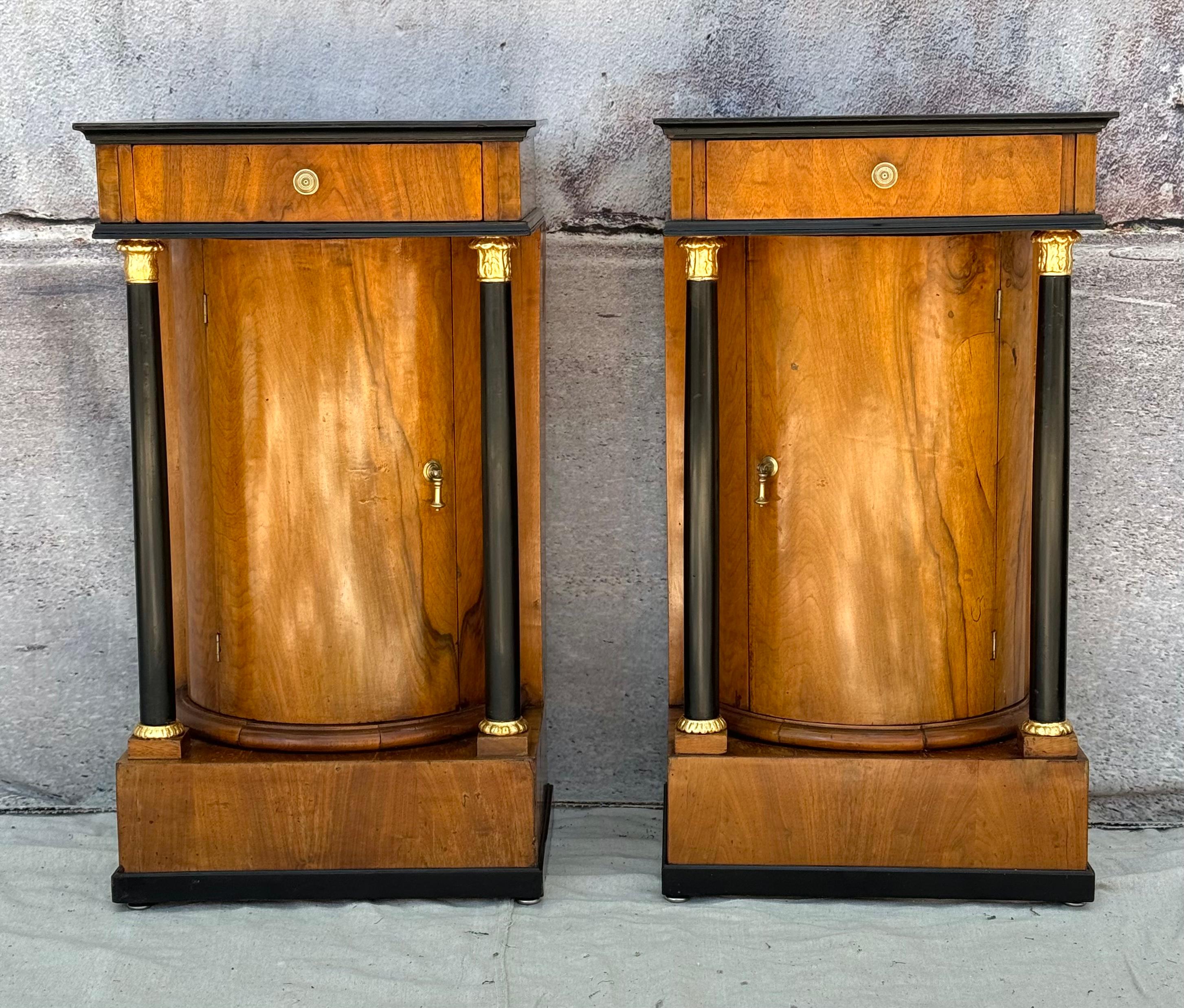Paar europäische Empirekommoden, frühes 19. Jahrhundert. Jede hat eine einzelne Schublade, die über der säulenartigen Einzeltür liegt. Die Kommoden sind mit je zwei ebonisierten und teilweise vergoldeten Säulen ausgestattet, die auf quadratischen