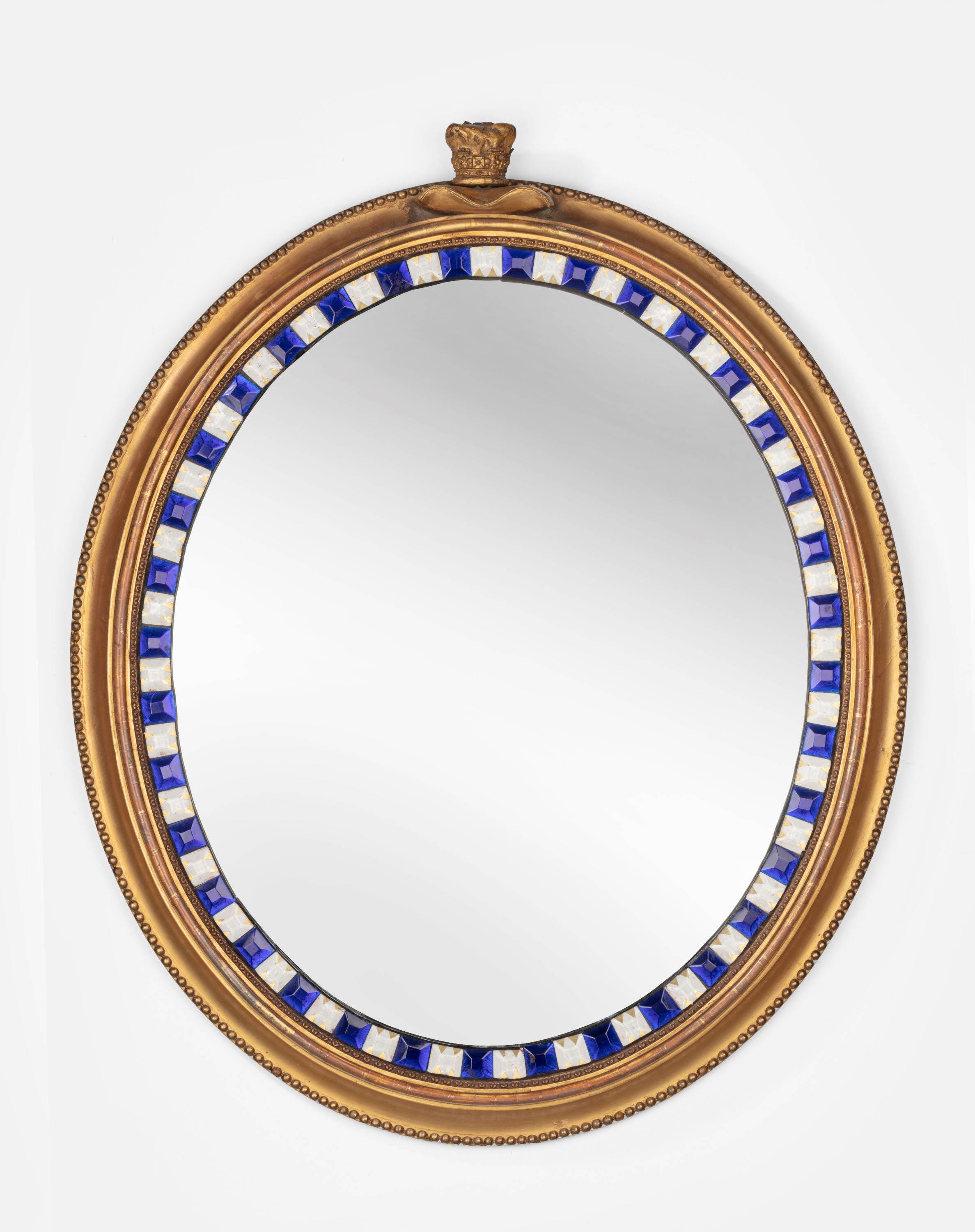 A rare pair of 19th century giltwood and glass, Irish, oval shaped mirrors. The borders of midnight blue buttons with old glass and gilded alternatives. Original gilding now somewhat tired. With a makers label dating from the 1830s.
  
