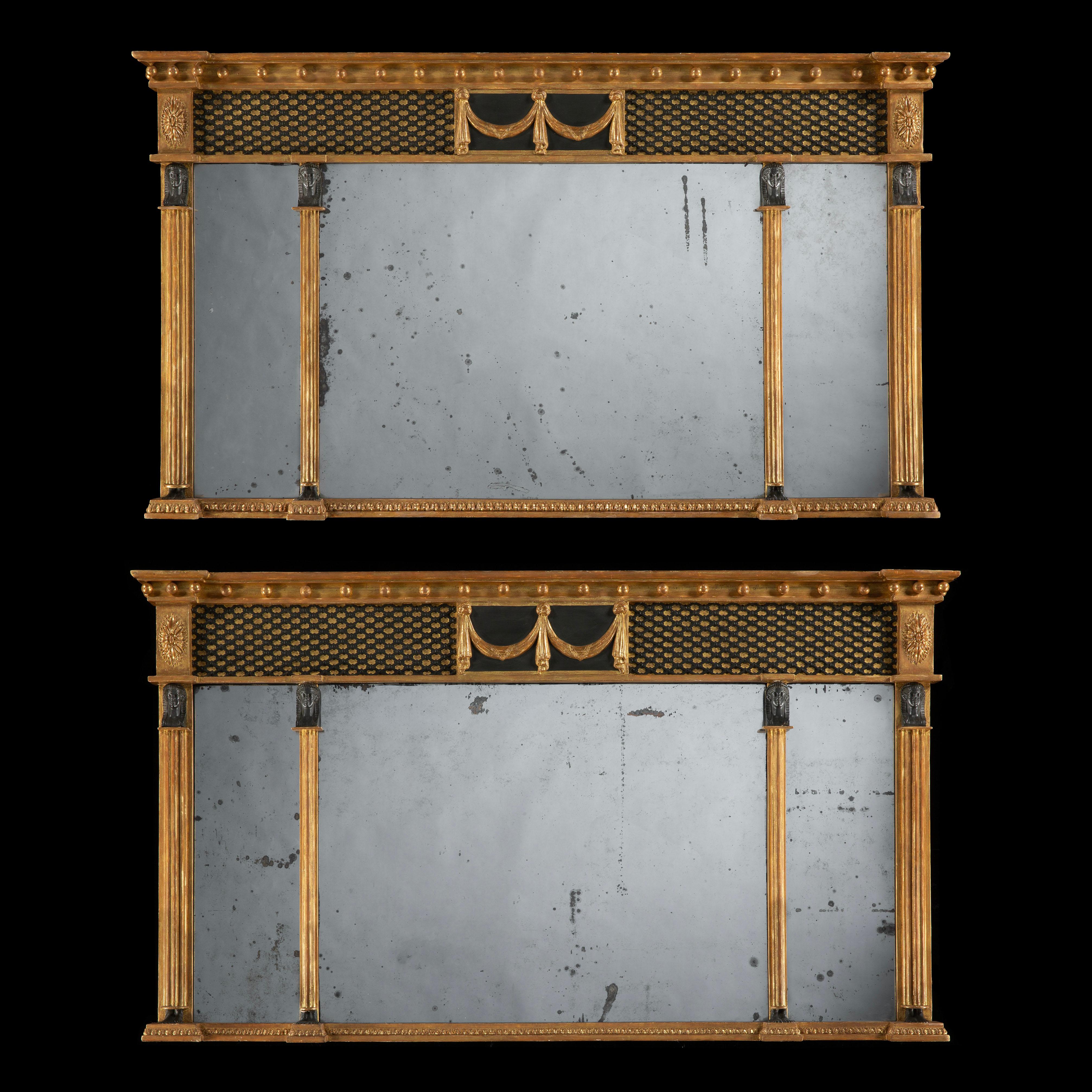 A Rare Pair of Regency Landscape Overmantle Mirrors 
In the Egyptian Manner

The triple mirrored plates are contained within giltwood framing, and each flanked by pharaonic herms. The upper section has 99ebonised tracery, with a central tablet with