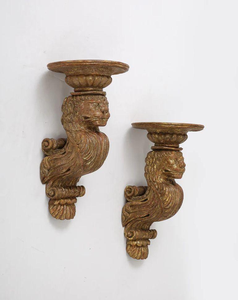 A rare and unusual pair of English wall brackets circa 1825-30 of carved lions holding a circular top, dry stripped to original gilding.It is likely that the inspiration for these brackets is French and that they were likely carved by immigrant