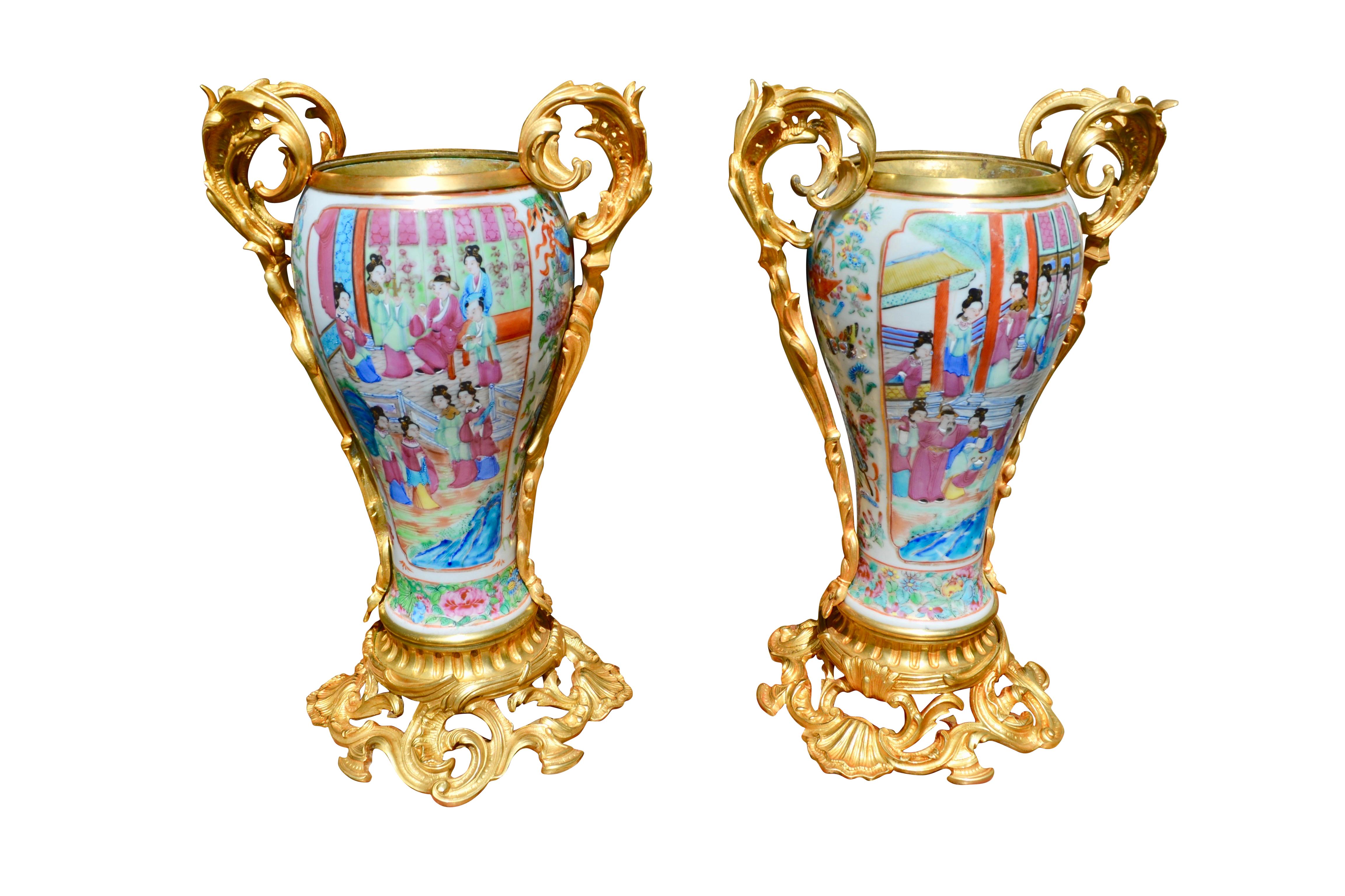 A beautiful French and Asian collaboration of a 19thC pair of Napoleon III Famille Rose porcelain, (from Canton China), and gilt bronze and brass oil lamps that miraculously include the original glass tube shades. The lamps are raised on an elegant