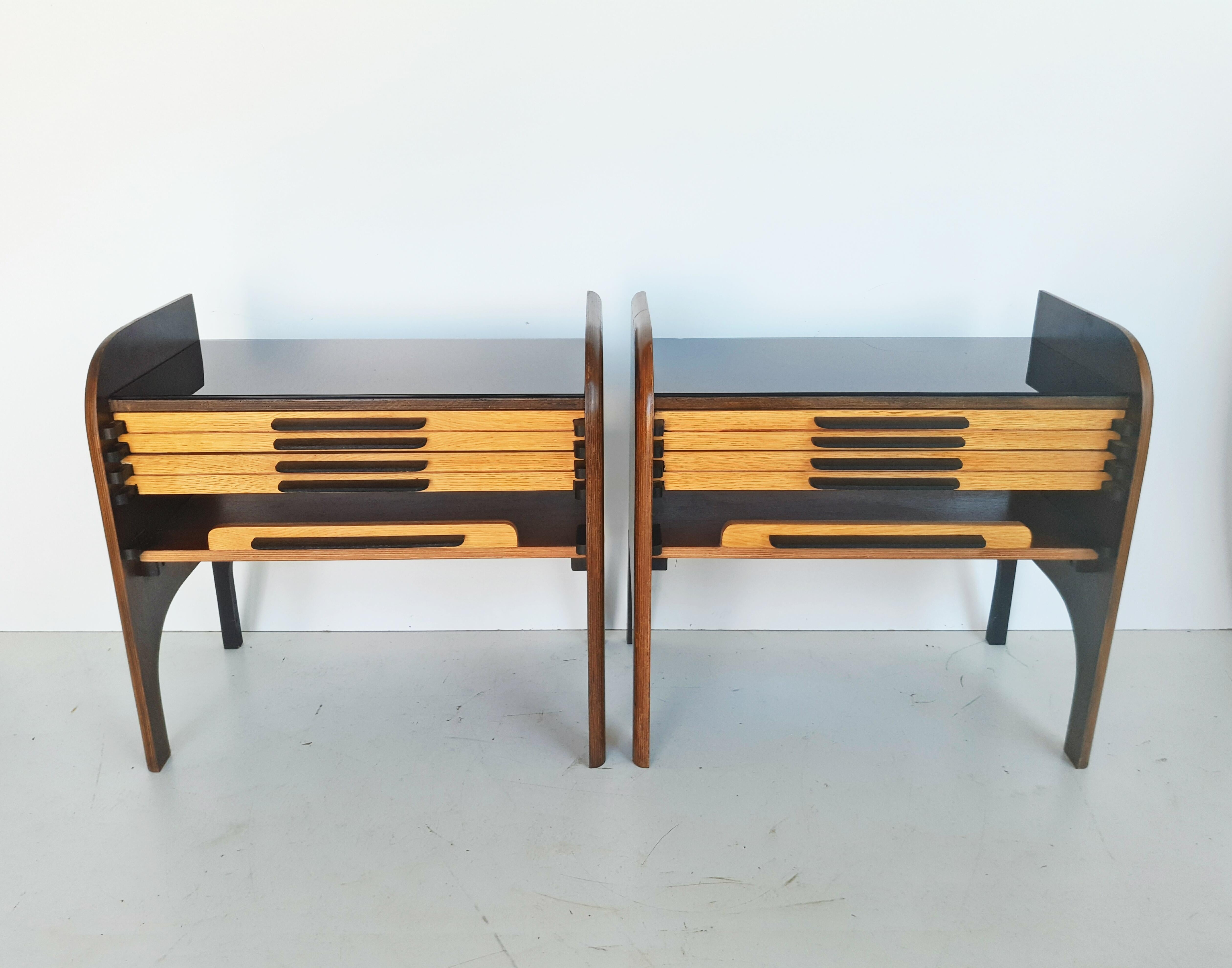 Beautiful and rare pair of French 1960s nightstands manufactured in France. The top is covered with smoked glass, and the rest is made entirely of wood. Each table is composed of three drawers.