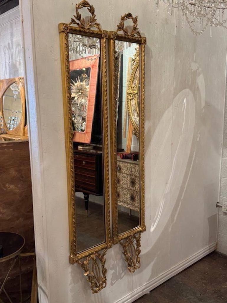 Rare pair of 19th century French Louis XVI giltwood narrow mirrors. These are prized for their vertical proportions, delicate carving, and warm gold patina. Circa 1870. 12.5w x 75h