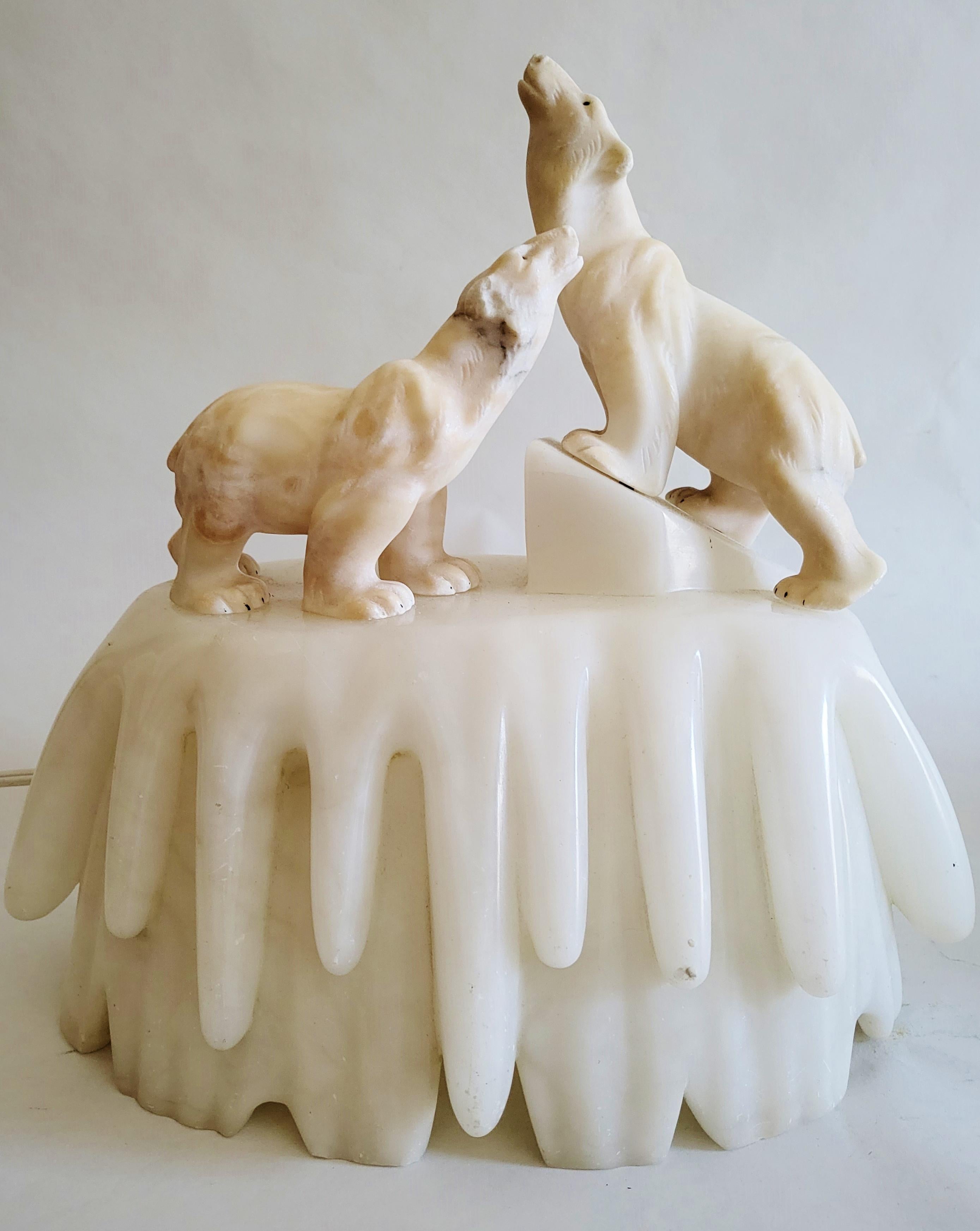 This stunning pair of Italian Art Deco figural accent lamps each portray a pair of beautifully carved alabaster polar bears standing on stylistically carved marble icebergs. The polar bears are affixed to the icebergs with metal rods and the