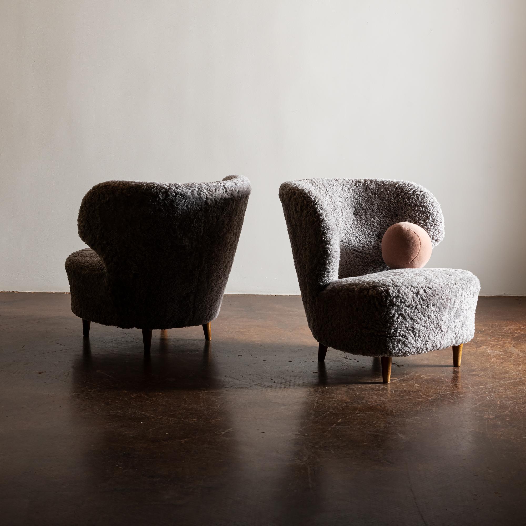 Rare pair of lounge chairs by Carl-Johan Boman, Finland, 1940s. These examples have a beautifully curved back and mounded seat, giving these chairs a graceful, substantial presence. This form contrasts nicely with the sheepskin texture and organic