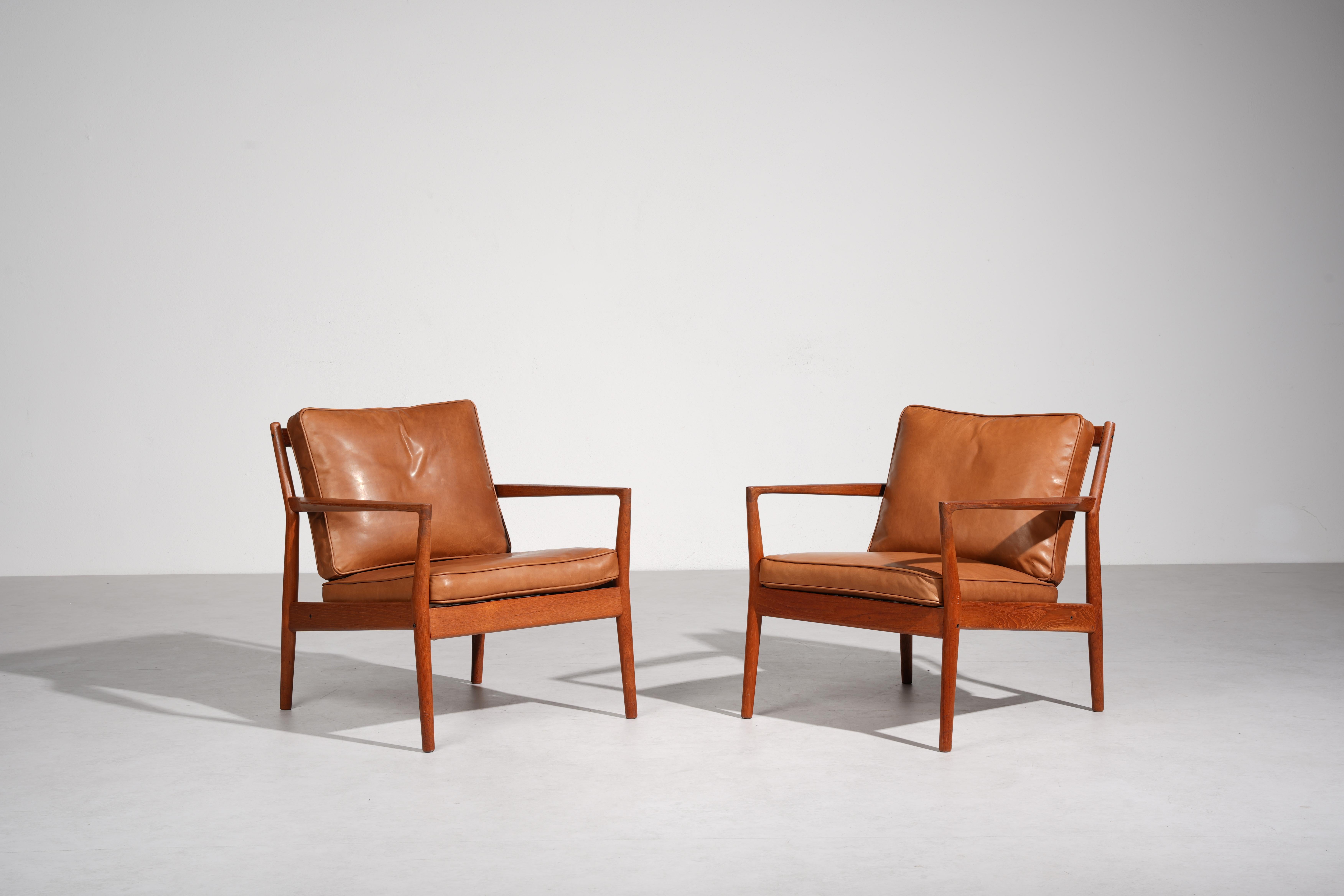 Un par de sillones de salón de madera de teca increíblemente raros, fabricados por Børge Jensen en Dinamarca en la década de 1960. Los bastidores presentan esculturales brazos de pala y lamas de respaldo en ángulo. Los cojines de plumas se han