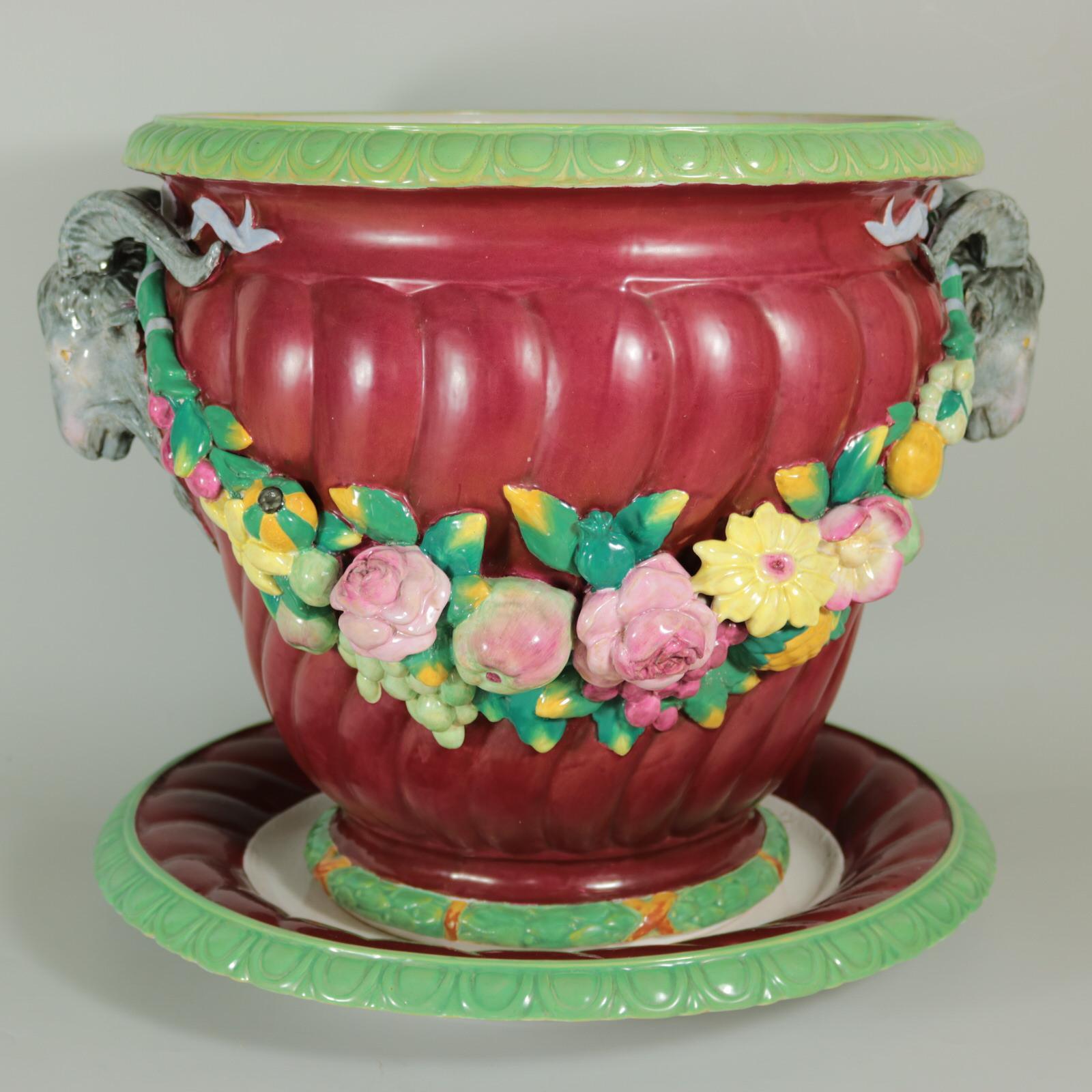 Pair of Minton Majolica jardinière and stands which feature ram's head handles and fruit swags. Rare, Magenta ground version. Colouration: magenta, green, pink, are predominant. Minton date cipher for the year 1853, impressed to the underside of one