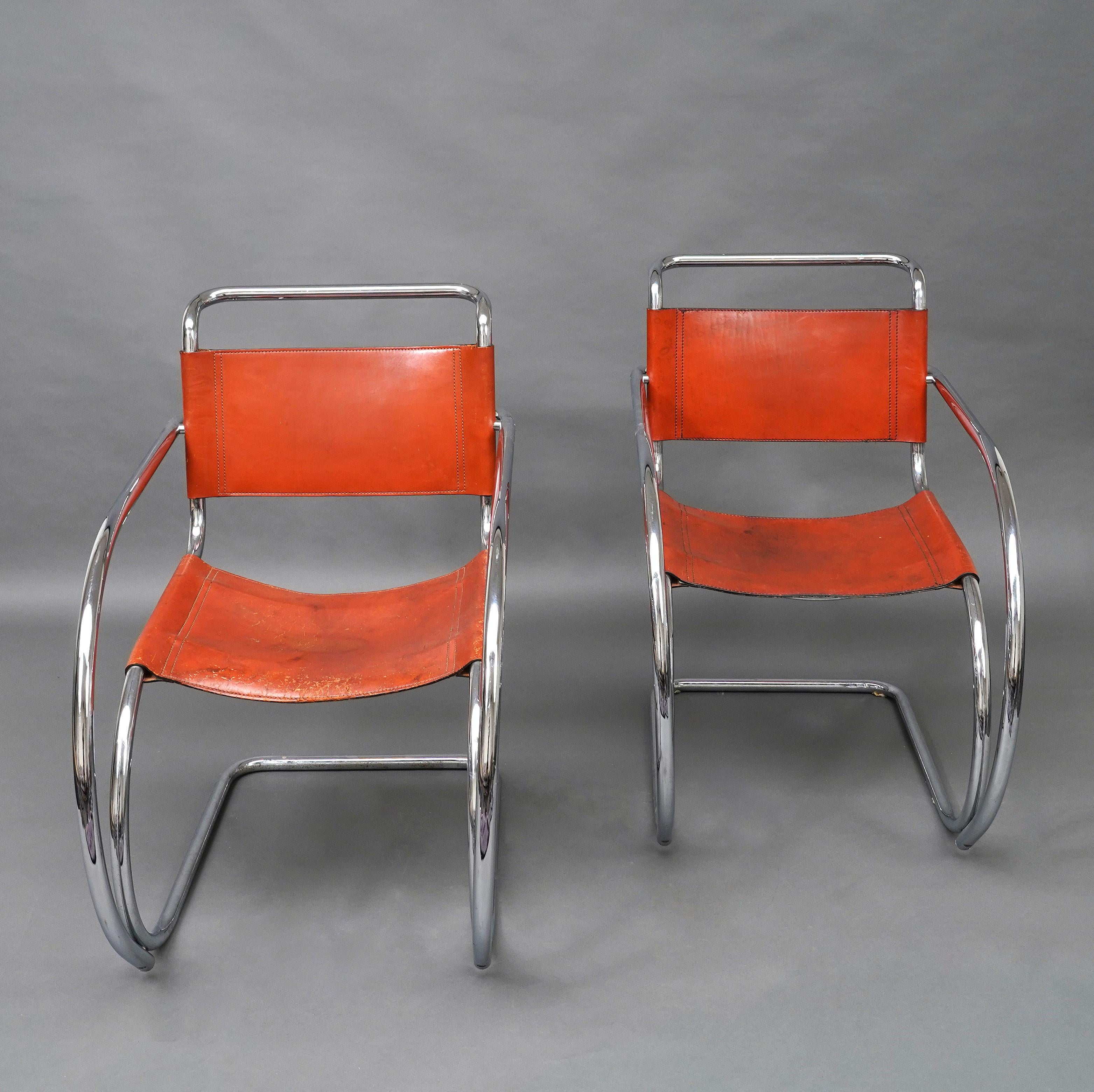 A  Paire de fauteuils Steel-Line en tubes d'acier chromé formant l'assise, les accoudoirs et les pieds en une seule pièce, avec cuir rouge patiné. 

Le fauteuil MR20 fait partie des premiers meubles en acier conçus par Mies van der Rohe. Le choix du