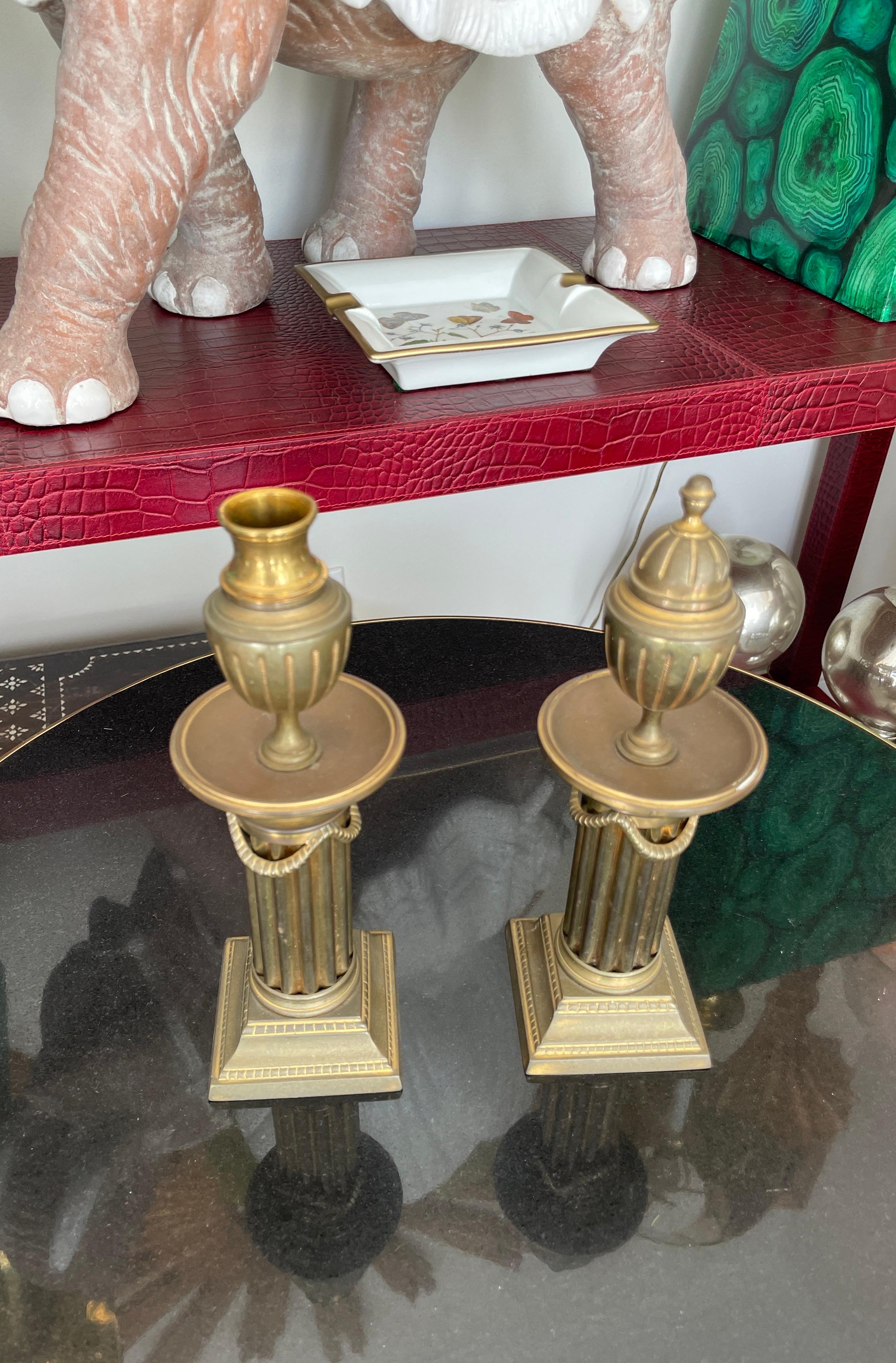 Rare paire de chandeliers italiens en laiton de style néoclassique. Ils ont la forme d'une colonne cannelée surmontée d'une urne. Le couvercle de l'urne se retourne pour accueillir la bougie.