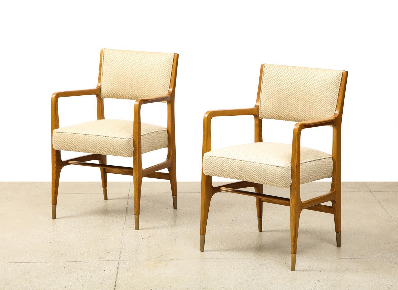 Rare pair of armchairs by Gio Ponti. A rare variation of model #110, produced by Cassina. Open-grain bleached ash frames with upholstered seat and back and brass sabots. Very good condition. Wood has been recently refinished and seats recently