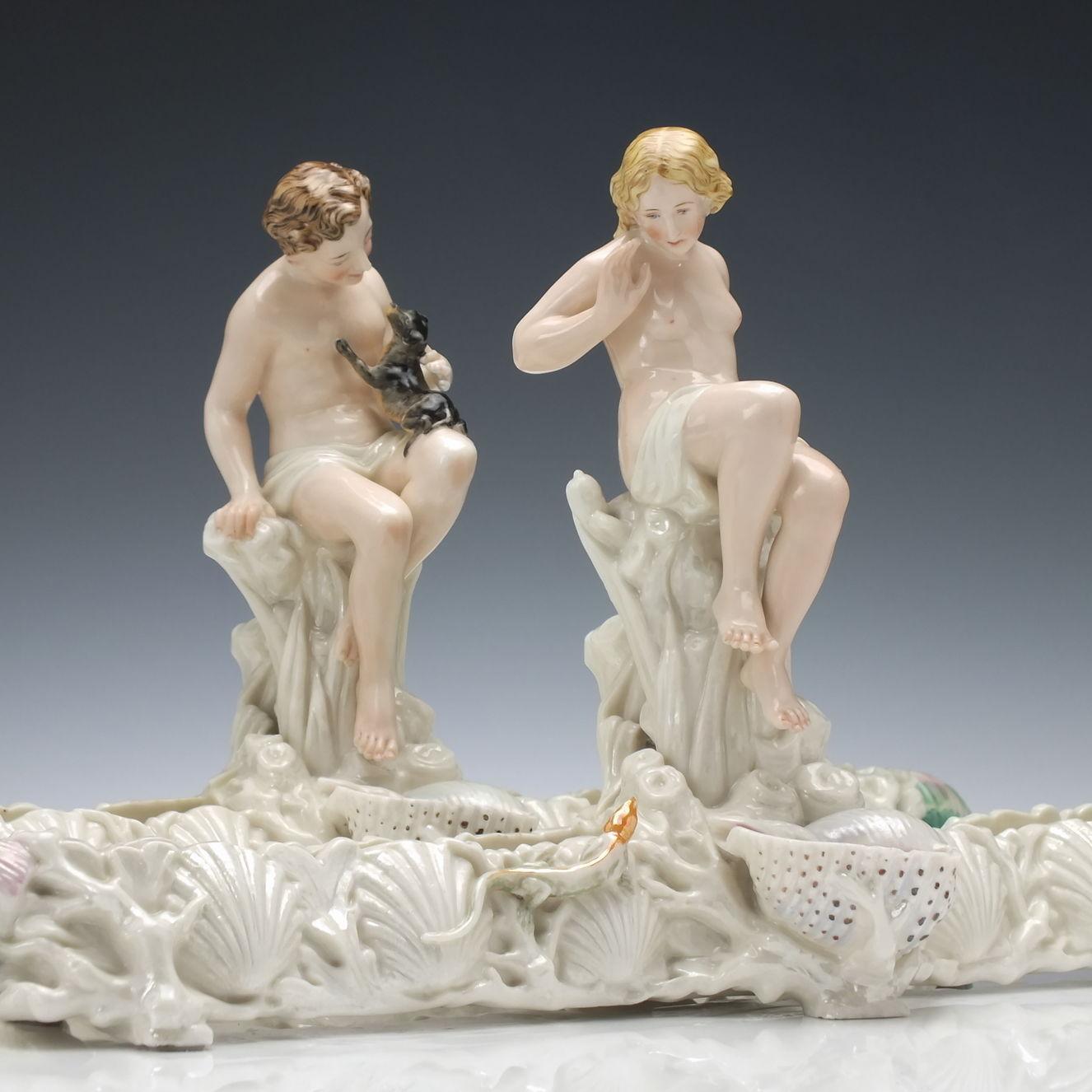 Technical description 

A very rare pair of Royal Worcester centerpieces. The long bases are decorated with shells. One piece also features a lizard on the base. The male piece features a man stroking a puppy on his lap. The female example shows