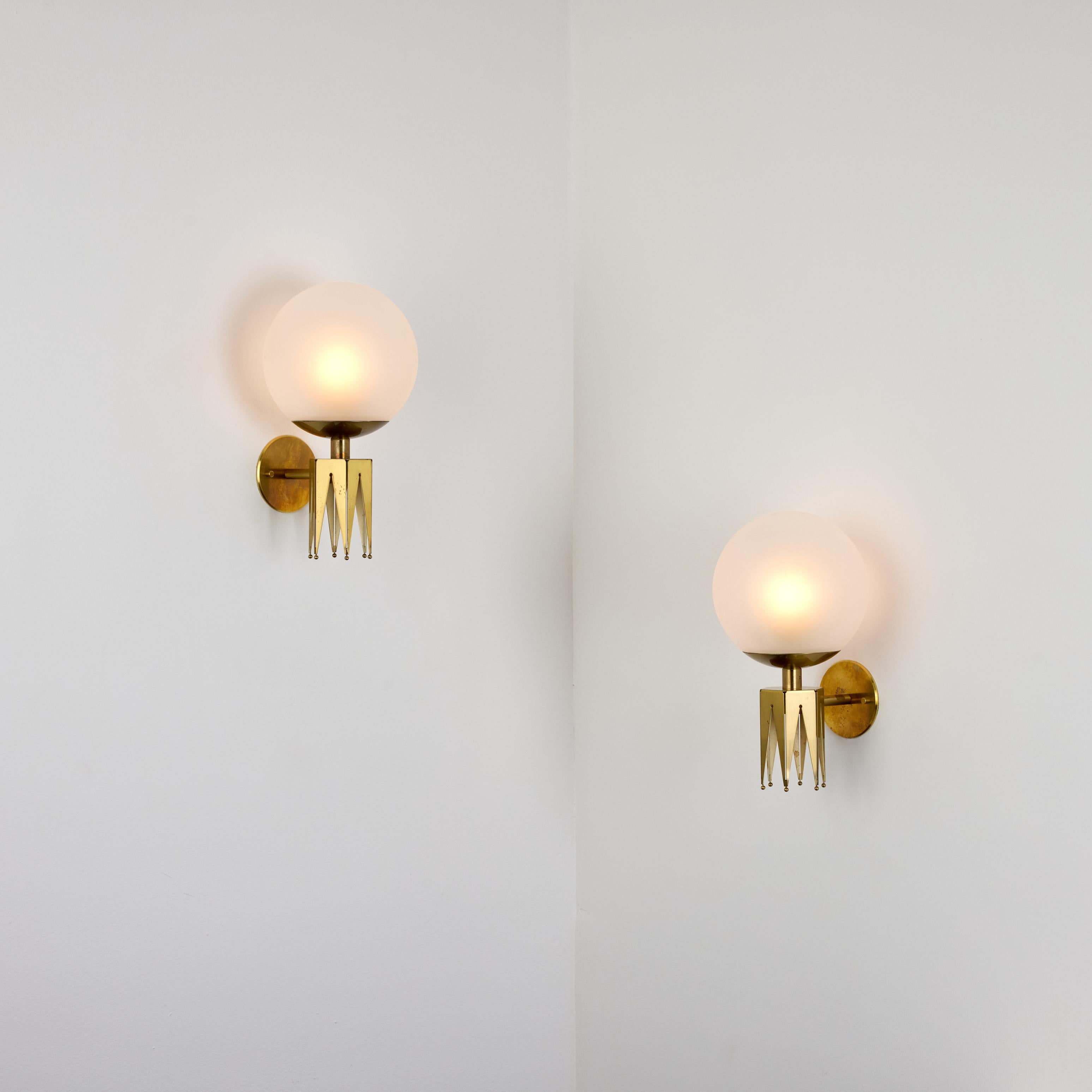 Rara coppia di lampade di Angelo Lelii per Arredoluce. Progettato e prodotto in Italia, intorno agli anni '1960. Orbite in vetro trasparente acidato abbinate ad armature a corona in ottone. Ogni applique contiene una singola presa di tipo E27,